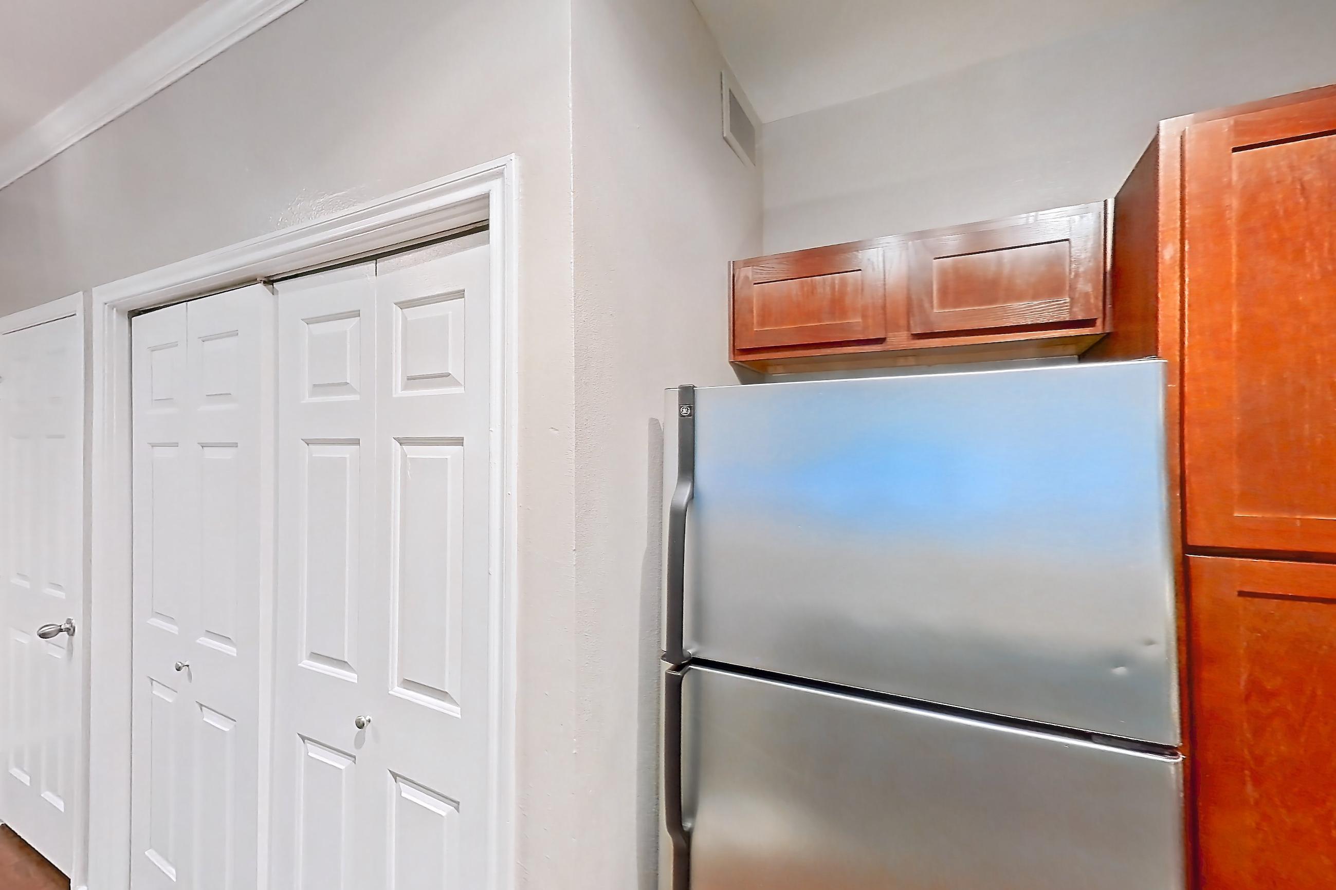 Kitchen with dishwasher, electric range, light stone countertops, light wood-finish flooring, microwave, oven/range, refrigerator, and stainless steel appliances, Apartment 0613 at Marquis at Barton Trails I