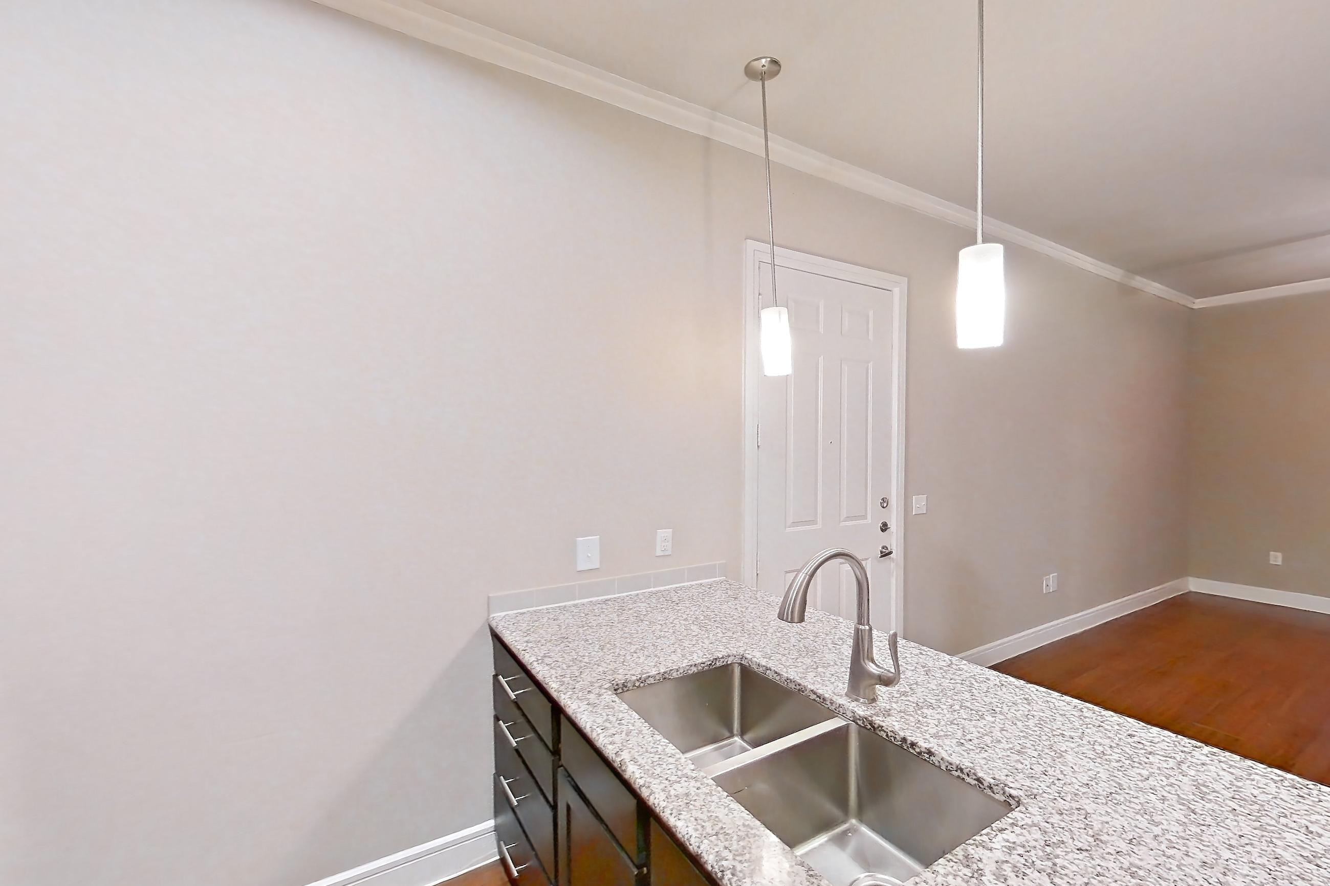 Kitchen with dark wood-finish flooring, dishwasher, electric range, light countertops, light stone countertops, light wood-finish flooring, microwave, oven/range, refrigerator, and stainless steel appliances, Apartment 0718 at Marquis at Barton Trails II