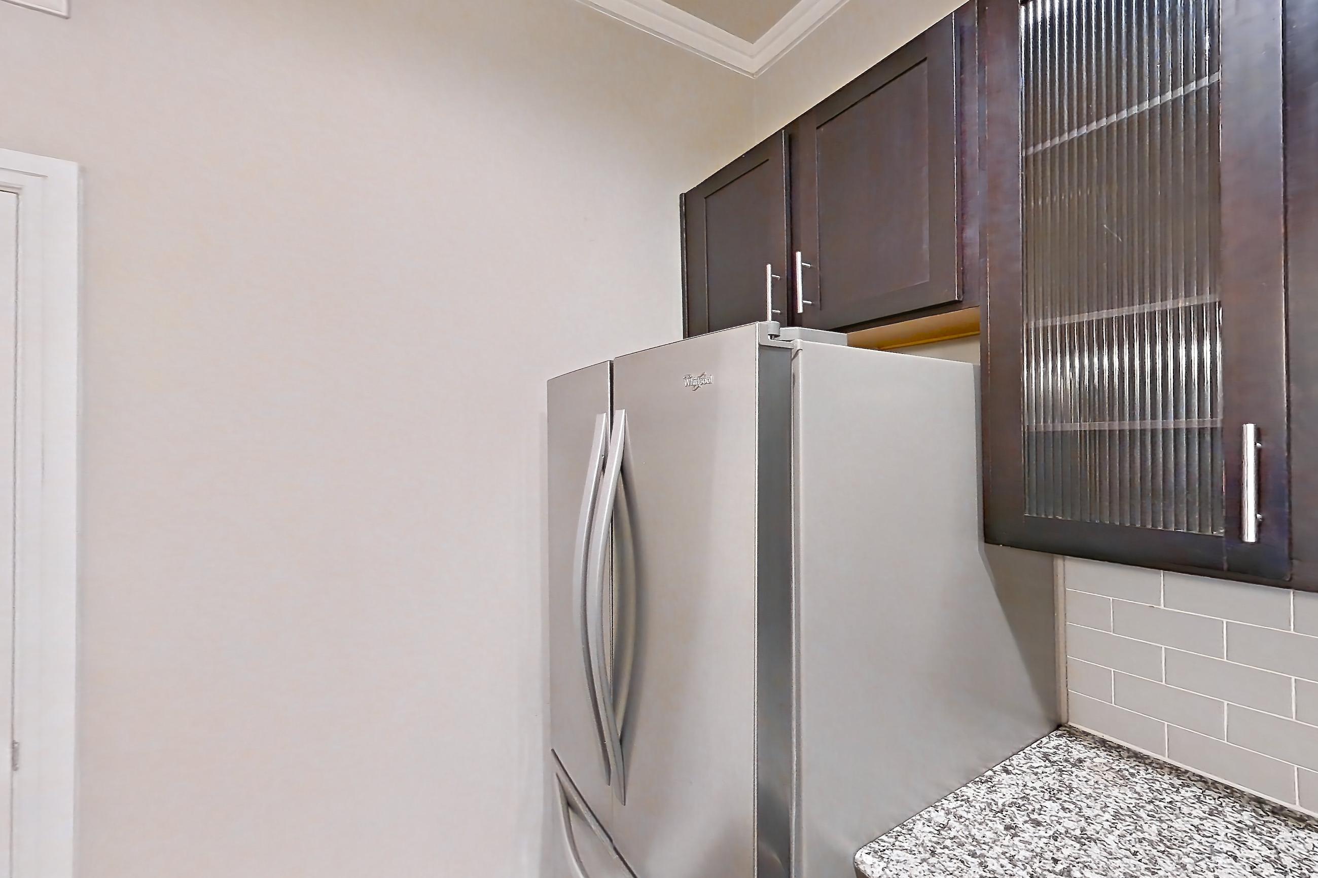 Kitchen with dark wood-finish flooring, dishwasher, electric range, light countertops, light stone countertops, light wood-finish flooring, microwave, oven/range, refrigerator, and stainless steel appliances, Apartment 0718 at Marquis at Barton Trails II