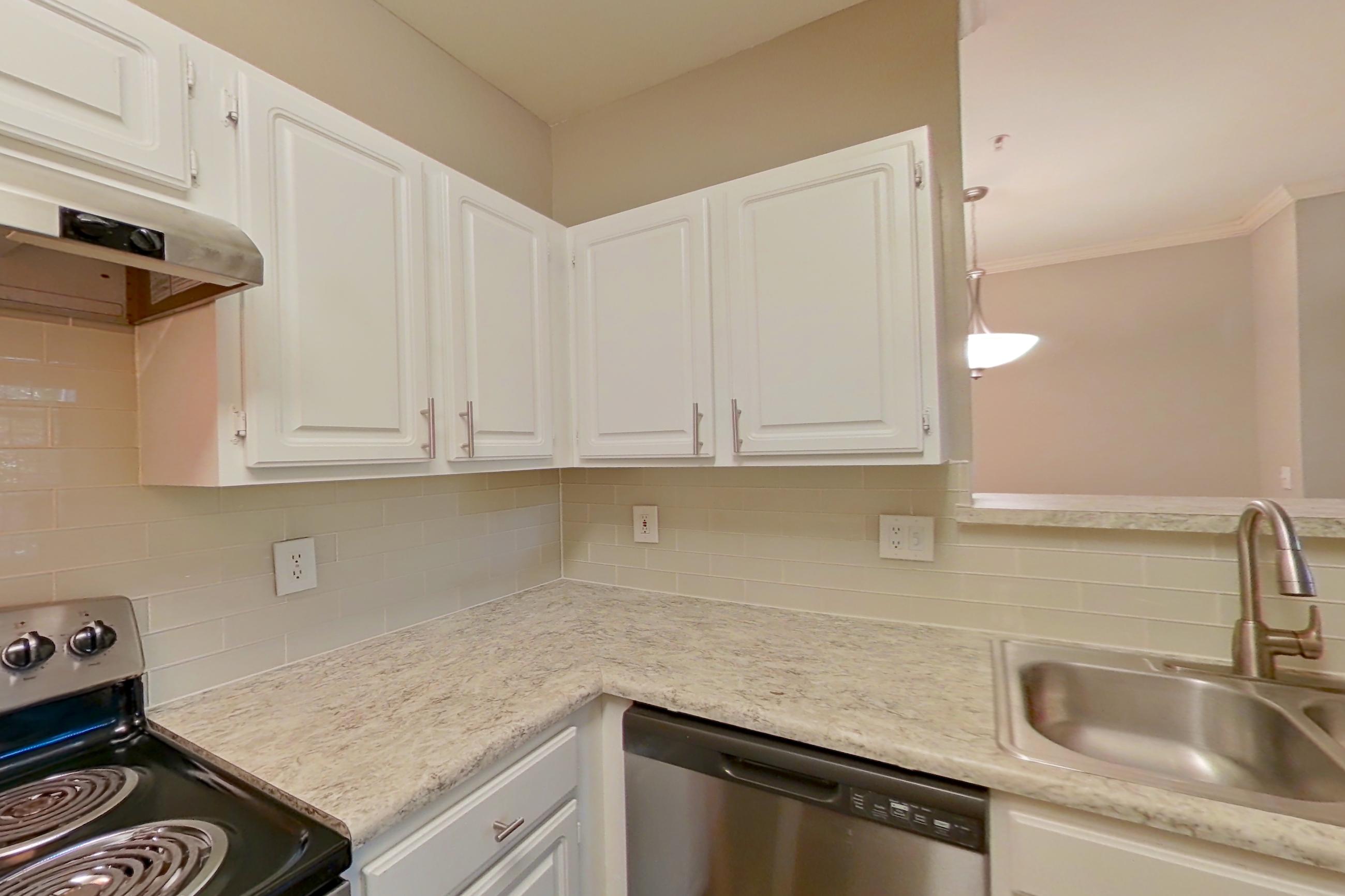 Kitchen with dark wood-finish flooring, dishwasher, electric range, light countertops, light stone countertops, oven/range, refrigerator, and stainless steel appliances, Apartment 0120 at The Marq at Brookhaven