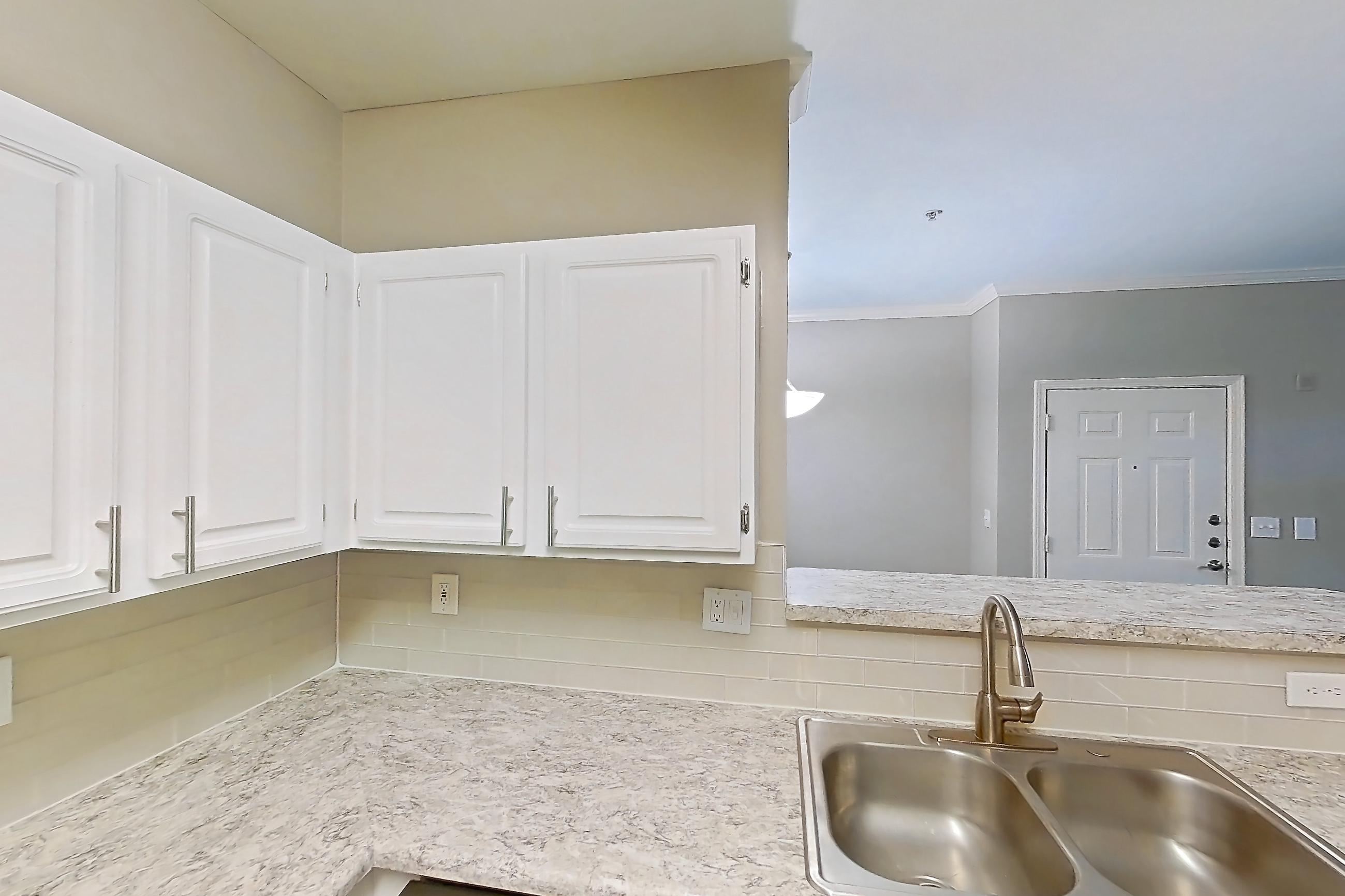 Kitchen with dark wood-finish flooring, dishwasher, electric range, light countertops, light stone countertops, microwave, oven/range, refrigerator, and stainless steel appliances, Apartment 0209 at The Marq at Brookhaven