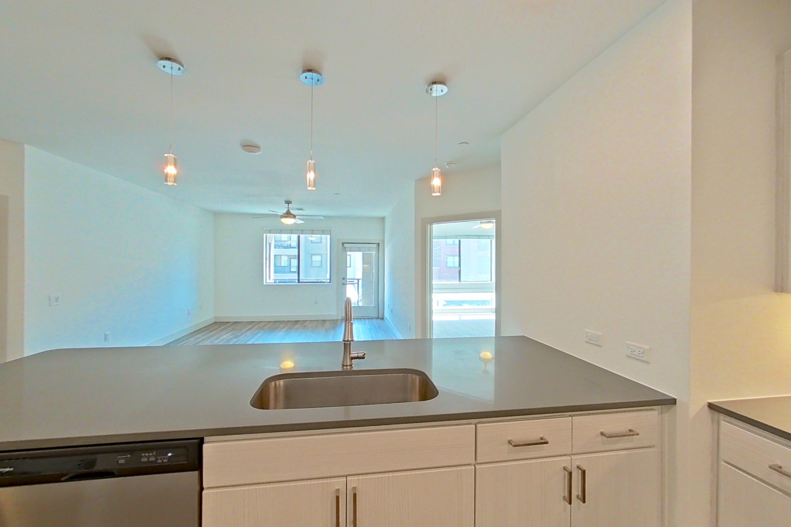 Kitchen with dark countertops, dark wood-finish flooring, dishwasher, electric range, light countertops, microwave, oven/range, and stainless steel appliances, Apartment 2090 at Marquis at Chandler