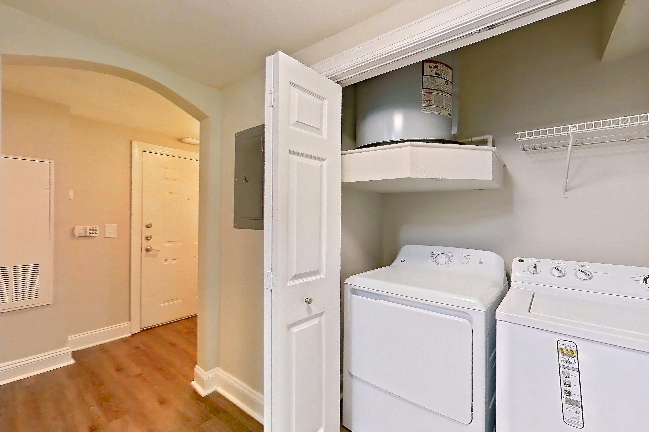 Kitchen with dark wood-finish flooring, electric range, in-unit laundry, light countertops, light stone countertops, light wood-finish flooring, microwave, oven/range, refrigerator, and stainless steel appliances, Apartment 1102 at Marq Perimeter