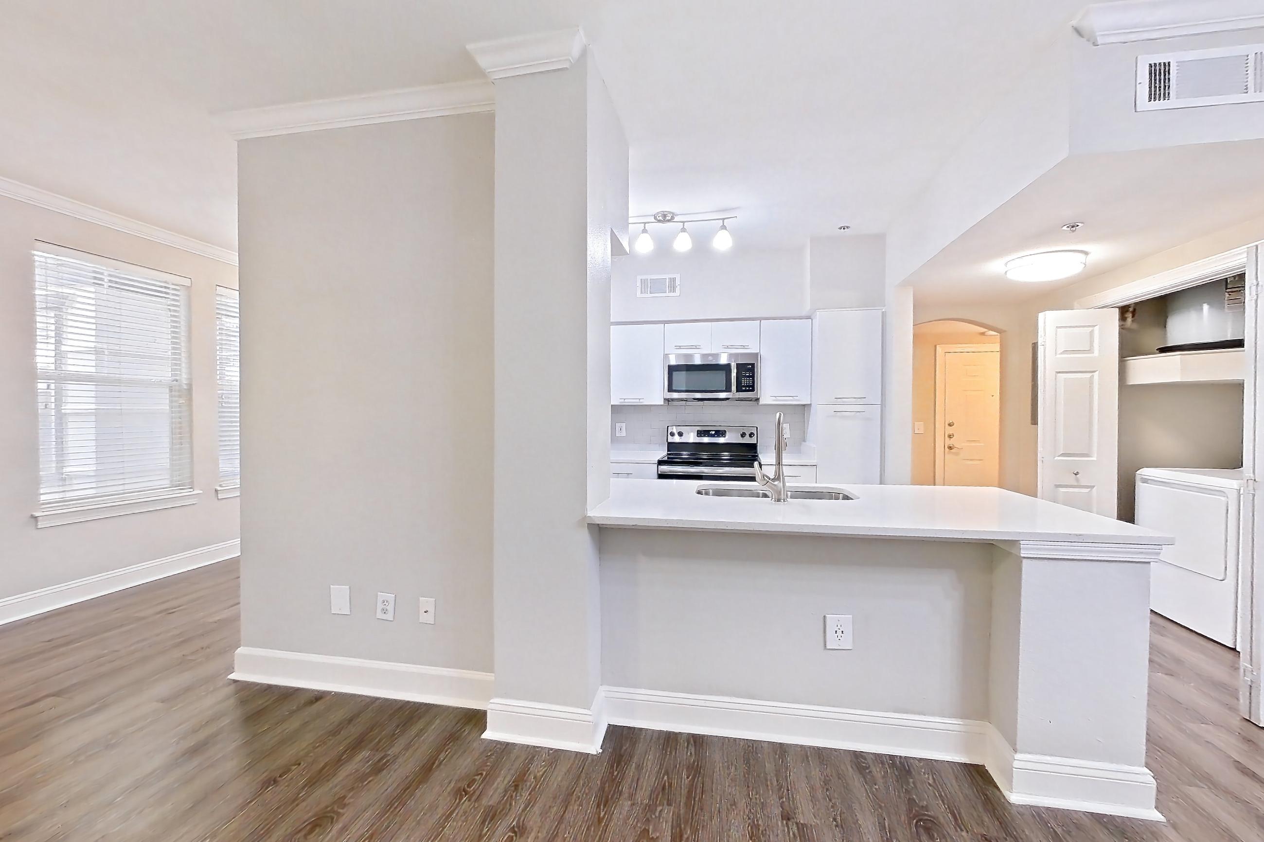 Living room with electric range, light countertops, microwave, oven/range, and stainless steel appliances, Apartment 1102 at Marq Perimeter