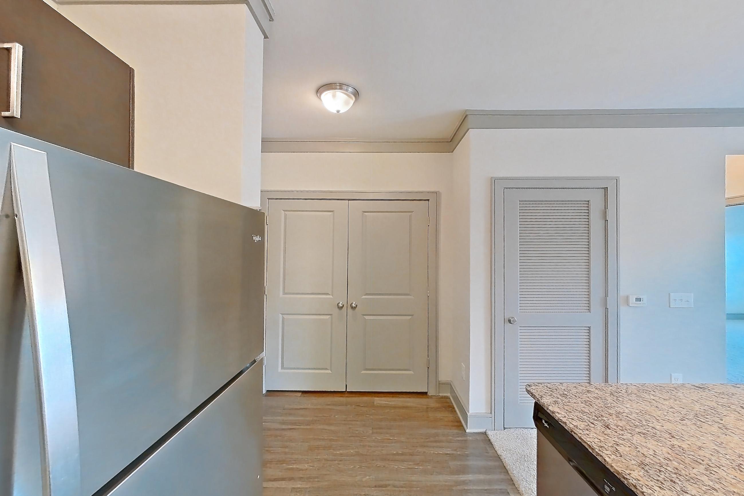 Kitchen with dishwasher, electric range, light stone countertops, light wood-finish flooring, microwave, oven/range, refrigerator, and stainless steel appliances, Apartment 1314 at Marquis Seven Meadows