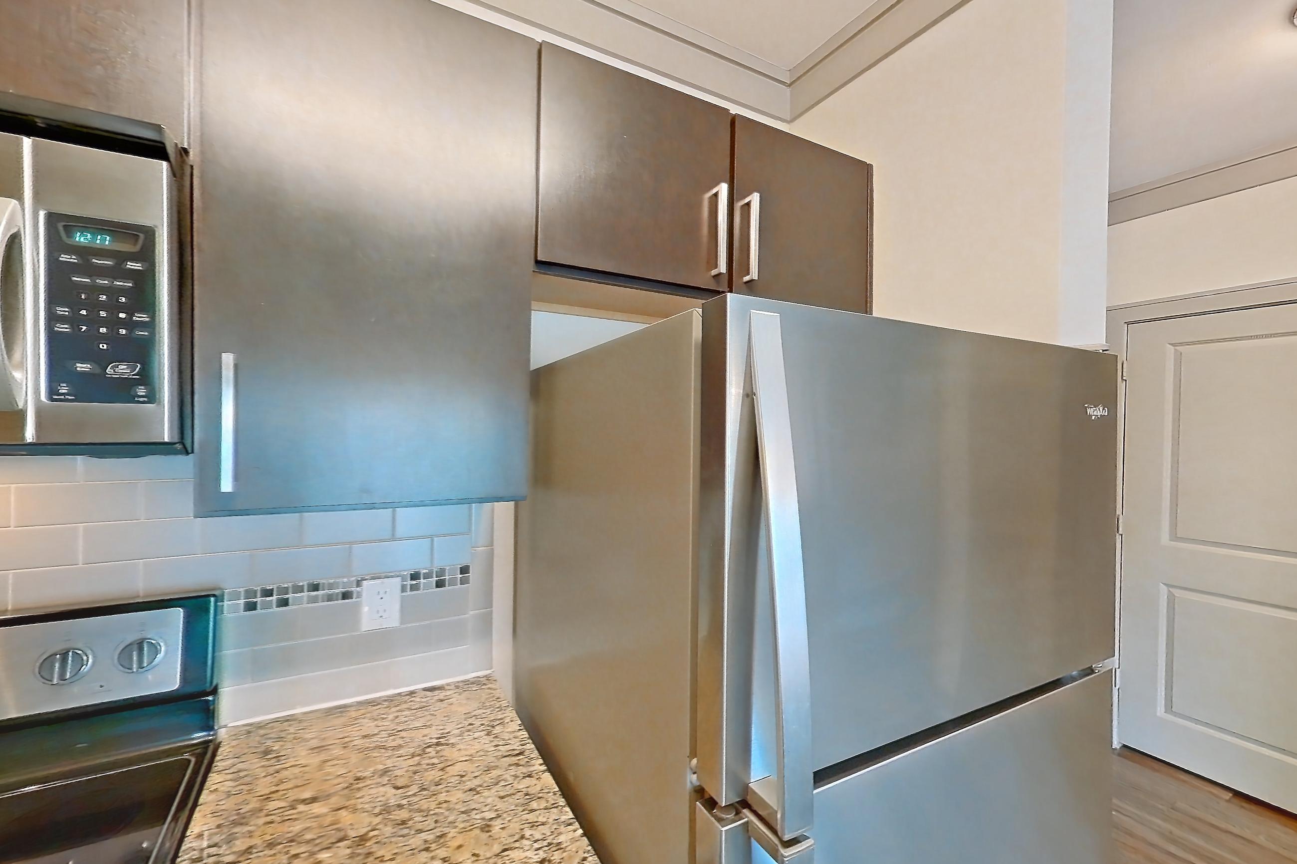 Kitchen with dishwasher, electric range, light stone countertops, light wood-finish flooring, microwave, oven/range, refrigerator, and stainless steel appliances, Apartment 1314 at Marquis Seven Meadows