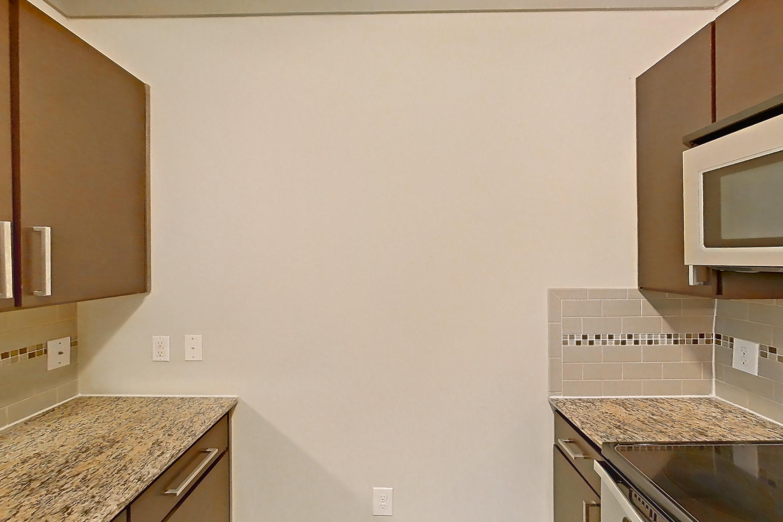 Kitchen with dishwasher, electric range, light stone countertops, light wood-finish flooring, microwave, oven/range, refrigerator, and stainless steel appliances, Apartment 1314 at Marquis Seven Meadows