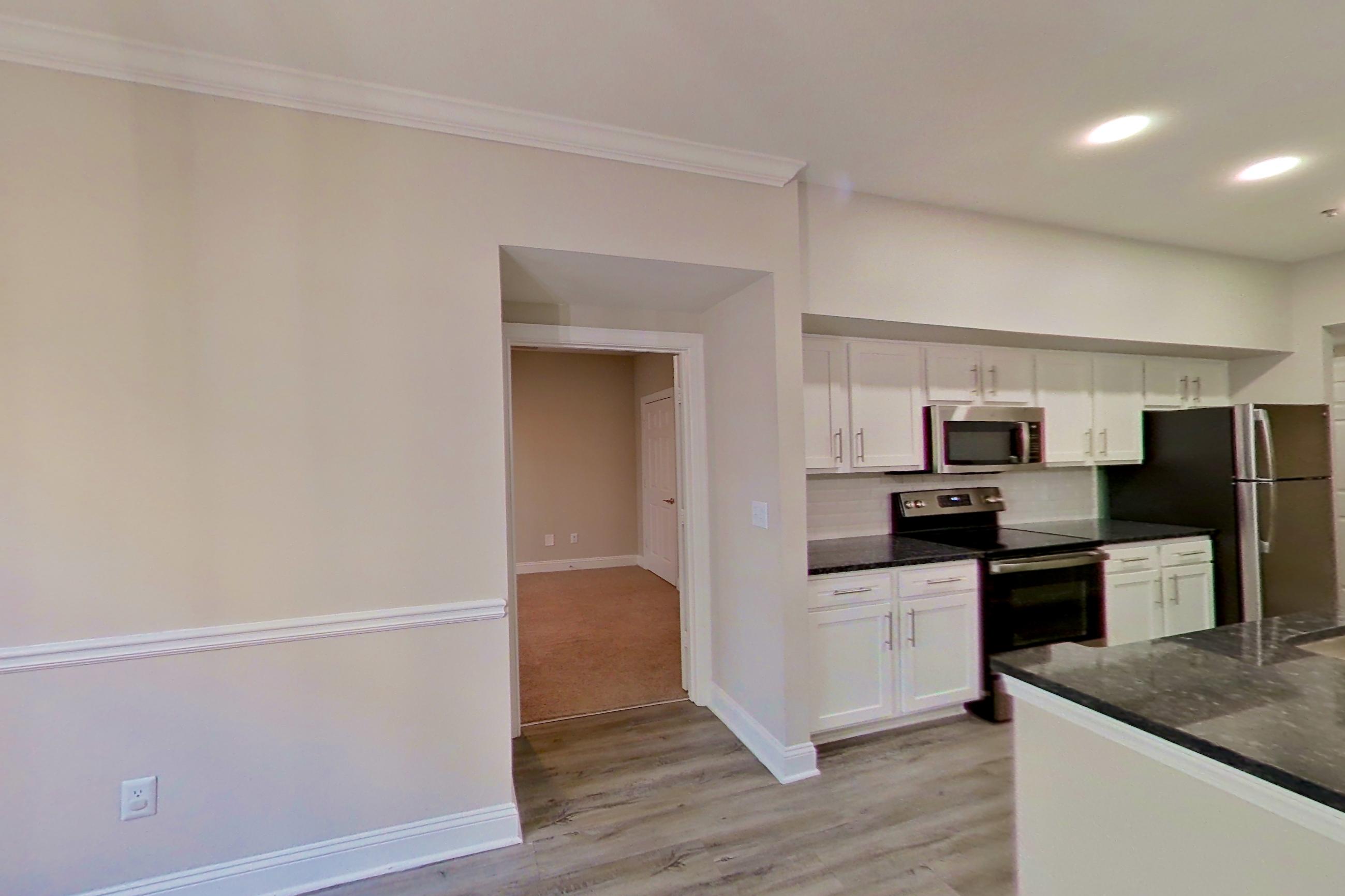 Dining area with dark stone countertops, electric range, light wood-finish flooring, oven/range, and stainless steel appliances, Apartment 2211 at Marq Perimeter