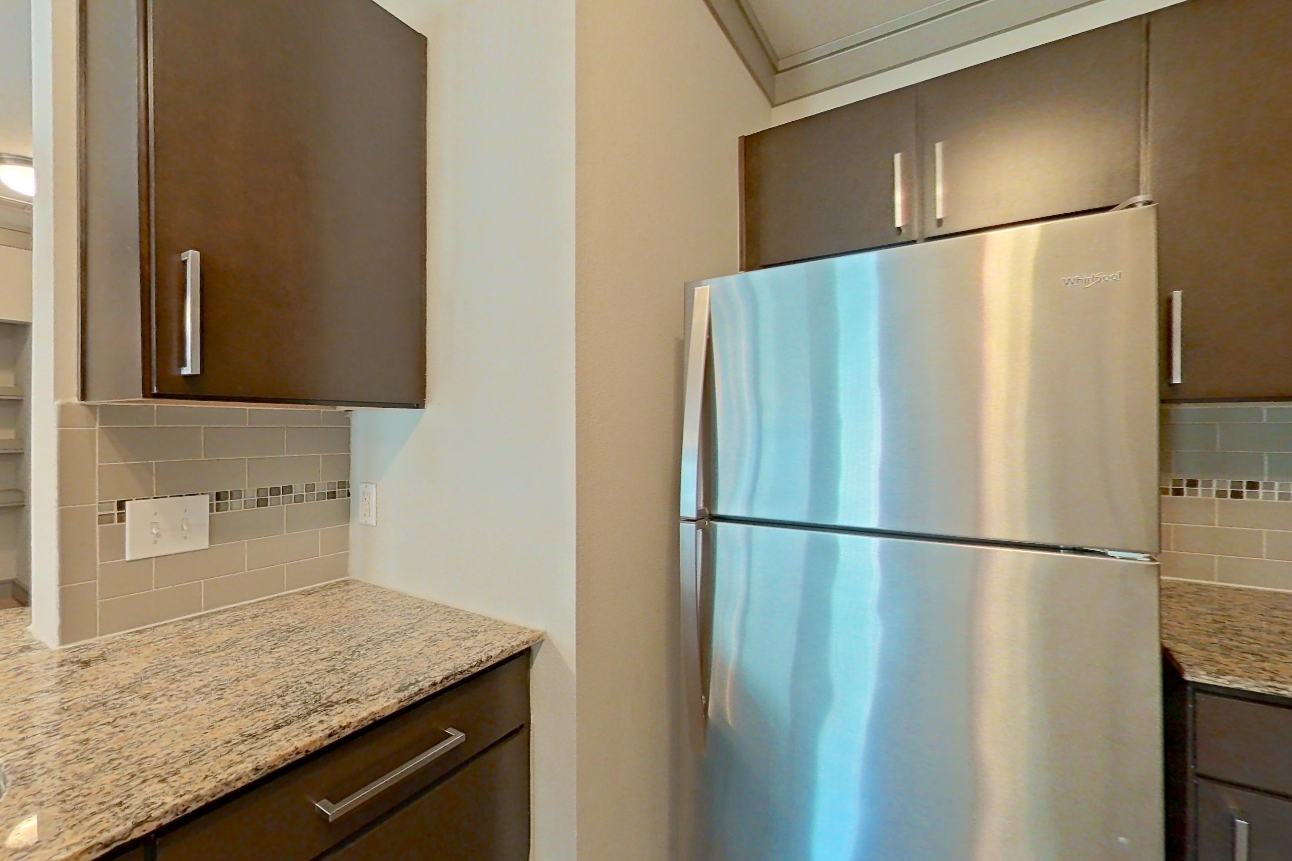 Kitchen with dishwasher, light stone countertops, refrigerator, and stainless steel appliances, Apartment 3309 at Marquis Seven Meadows