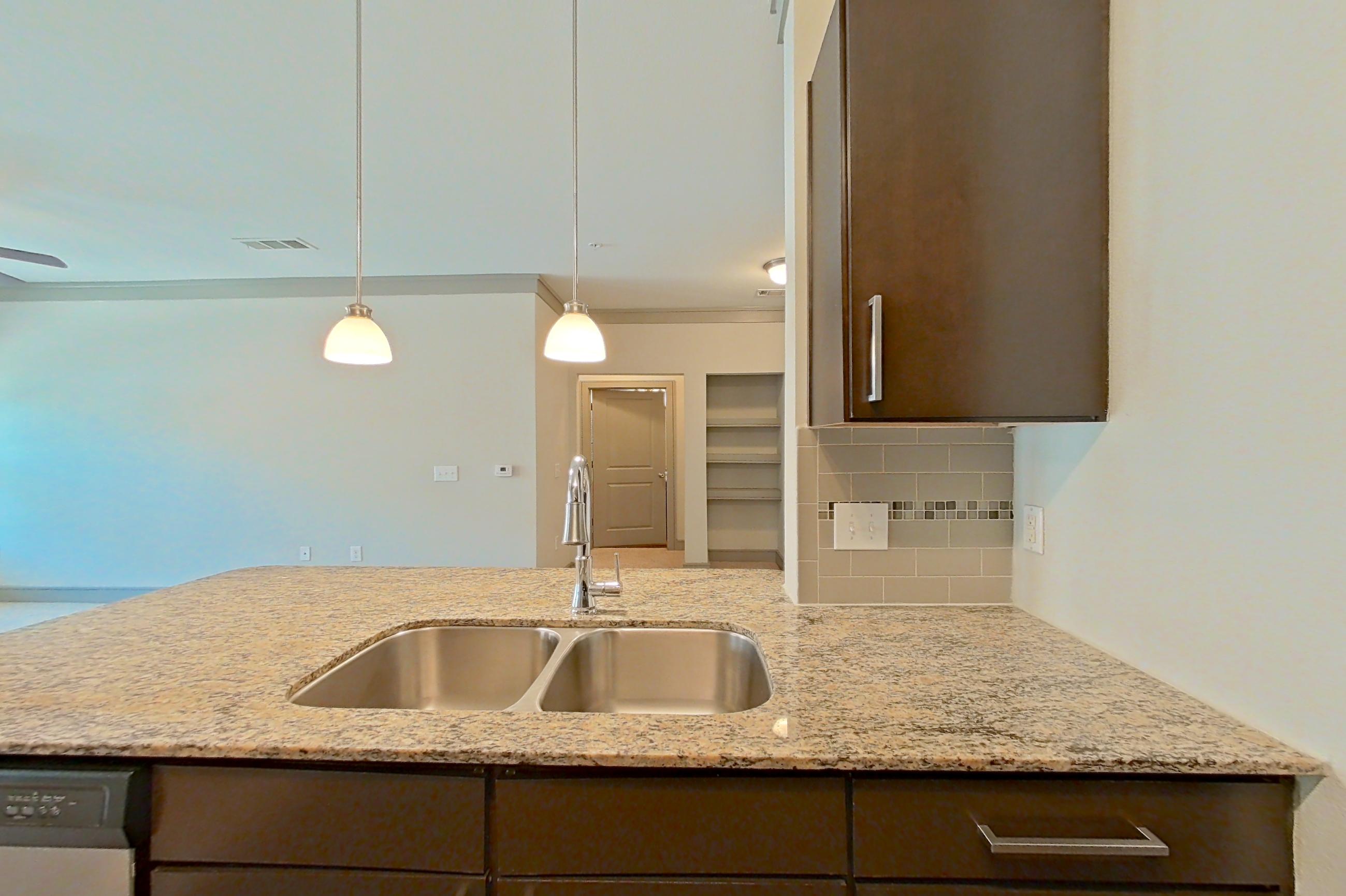 Kitchen with dishwasher, light stone countertops, refrigerator, and stainless steel appliances, Apartment 3309 at Marquis Seven Meadows