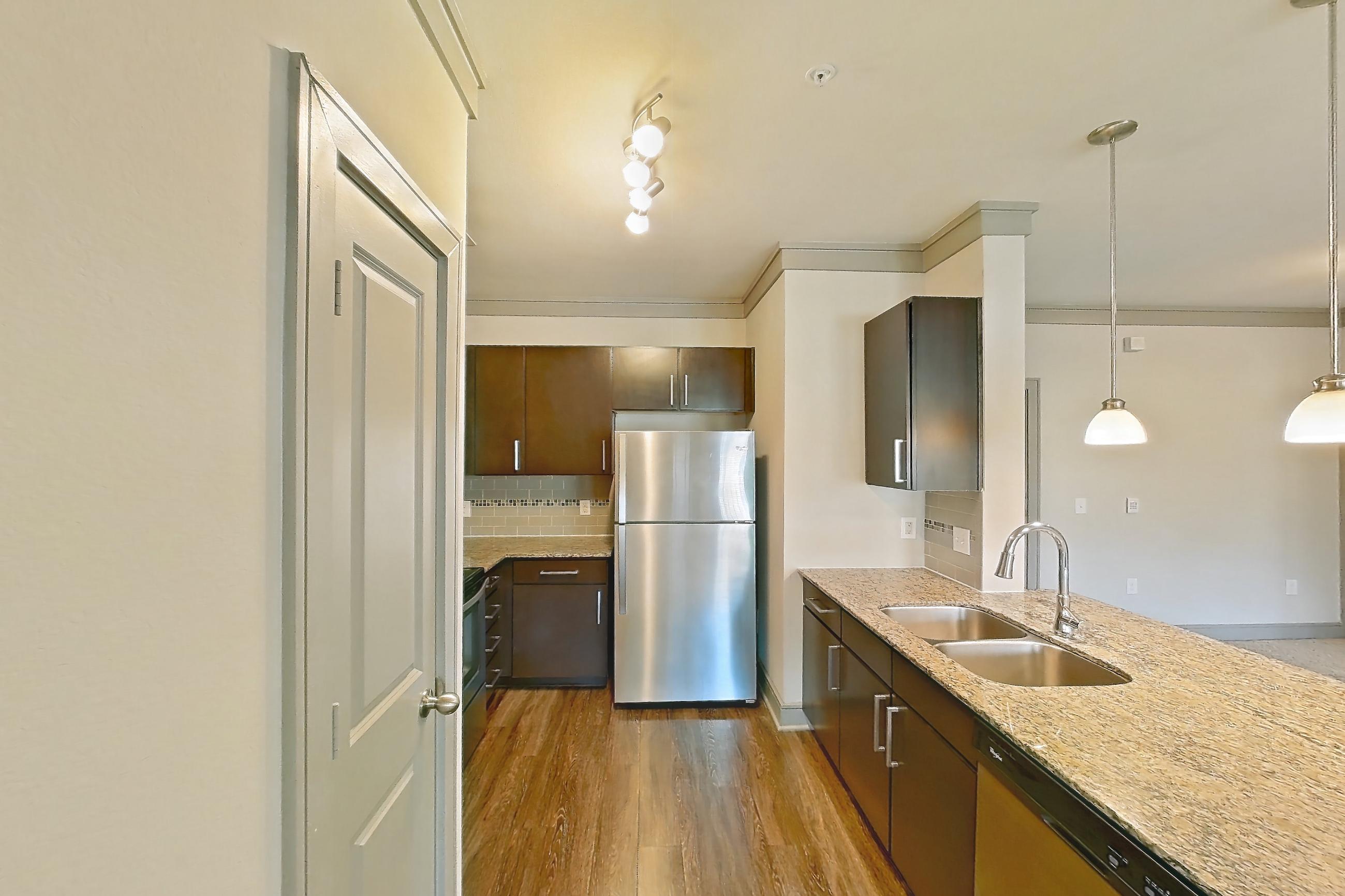 Kitchen space with dishwasher, light carpet, light stone countertops, light wood-finish flooring, and stainless steel appliances, Apartment 3312 at Marquis Seven Meadows