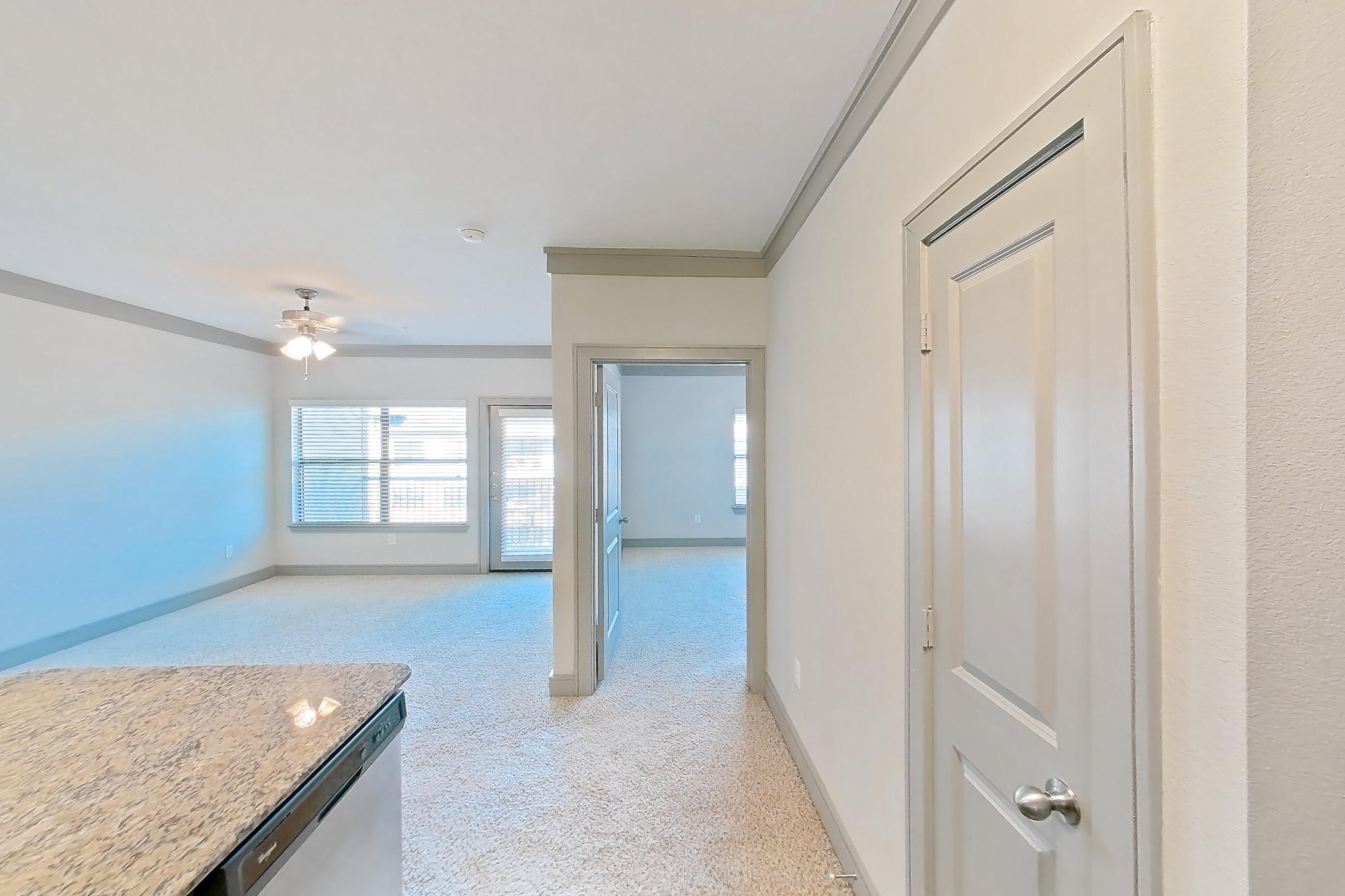 Kitchen with dishwasher, electric range, light carpet, light countertops, light stone countertops, light wood-finish flooring, microwave, oven/range, and stainless steel appliances, Apartment 3312 at Marquis Seven Meadows