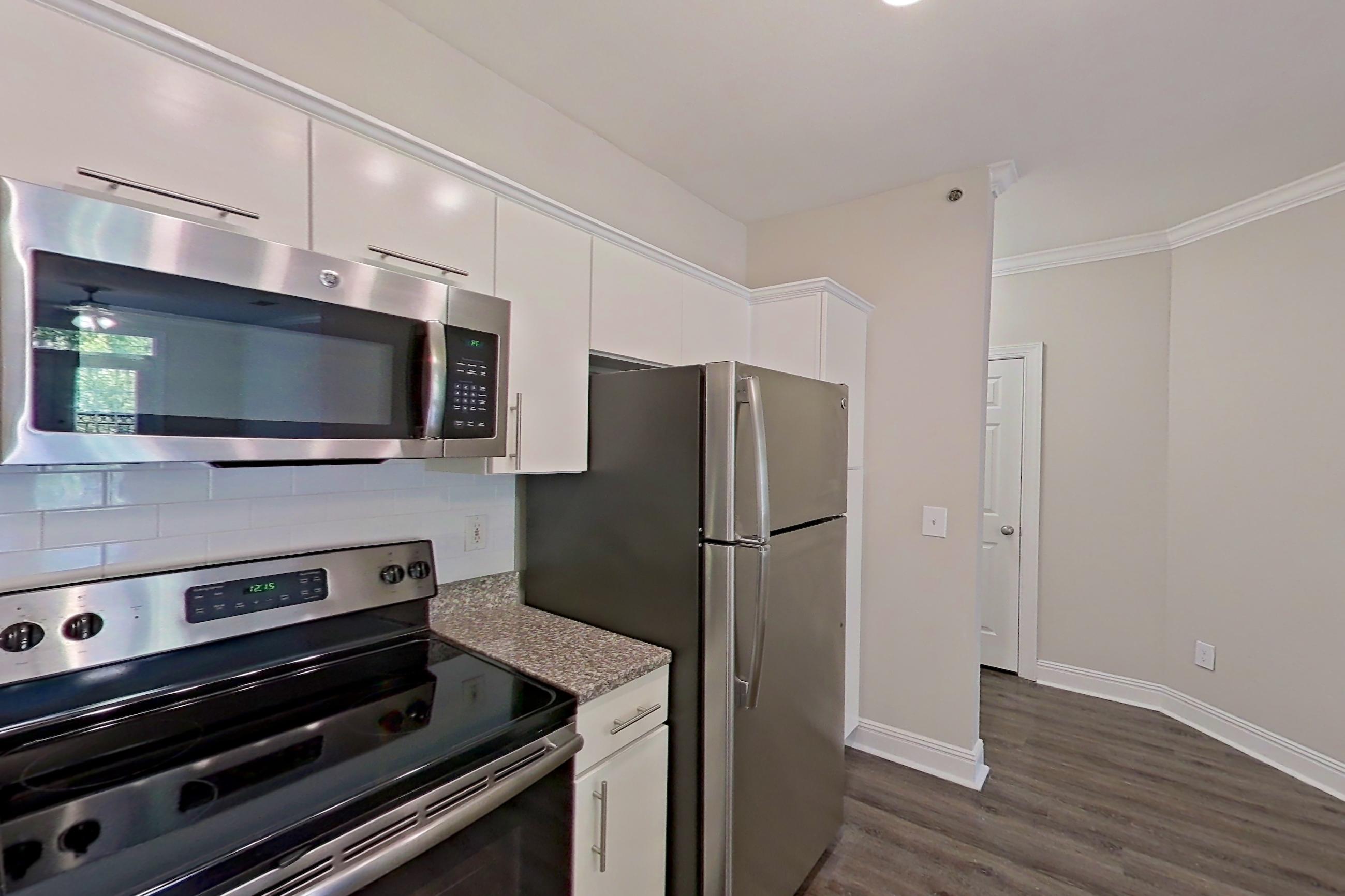Kitchen with dark wood-finish flooring, electric range, light countertops, light stone countertops, microwave, oven/range, refrigerator, and stainless steel appliances, Apartment 2514 at Marq Perimeter