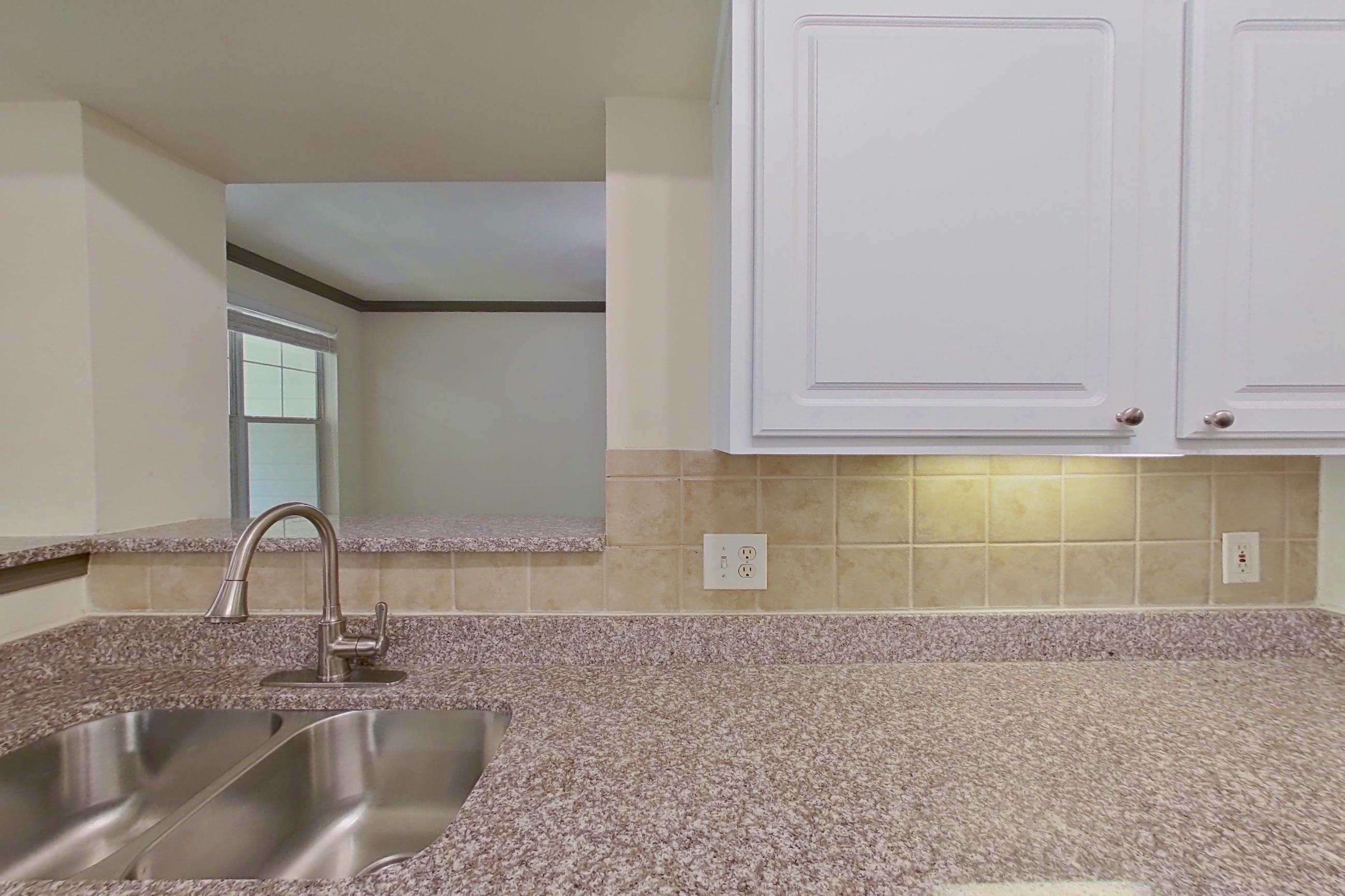 Kitchen with black appliances, dishwasher, electric range, light countertops, light stone countertops, light wood-finish flooring, microwave, oven/range, refrigerator, and stainless steel appliances, Apartment 3110 at Marq Perimeter