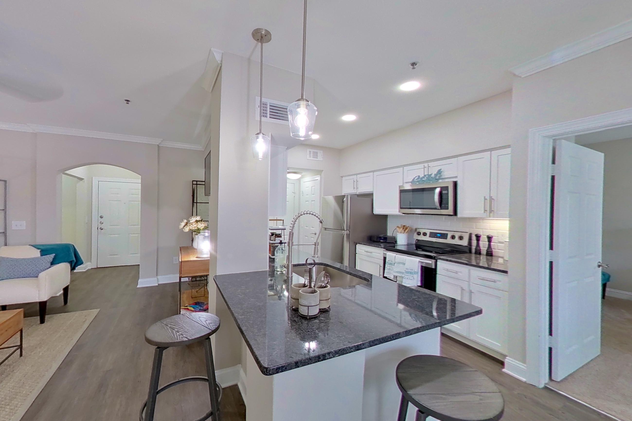 Dining area with dark stone countertops, dark wood-finish flooring, electric range, kitchen island, oven/range, refrigerator, and stainless steel appliances, Apartment 3201 at Marq Perimeter