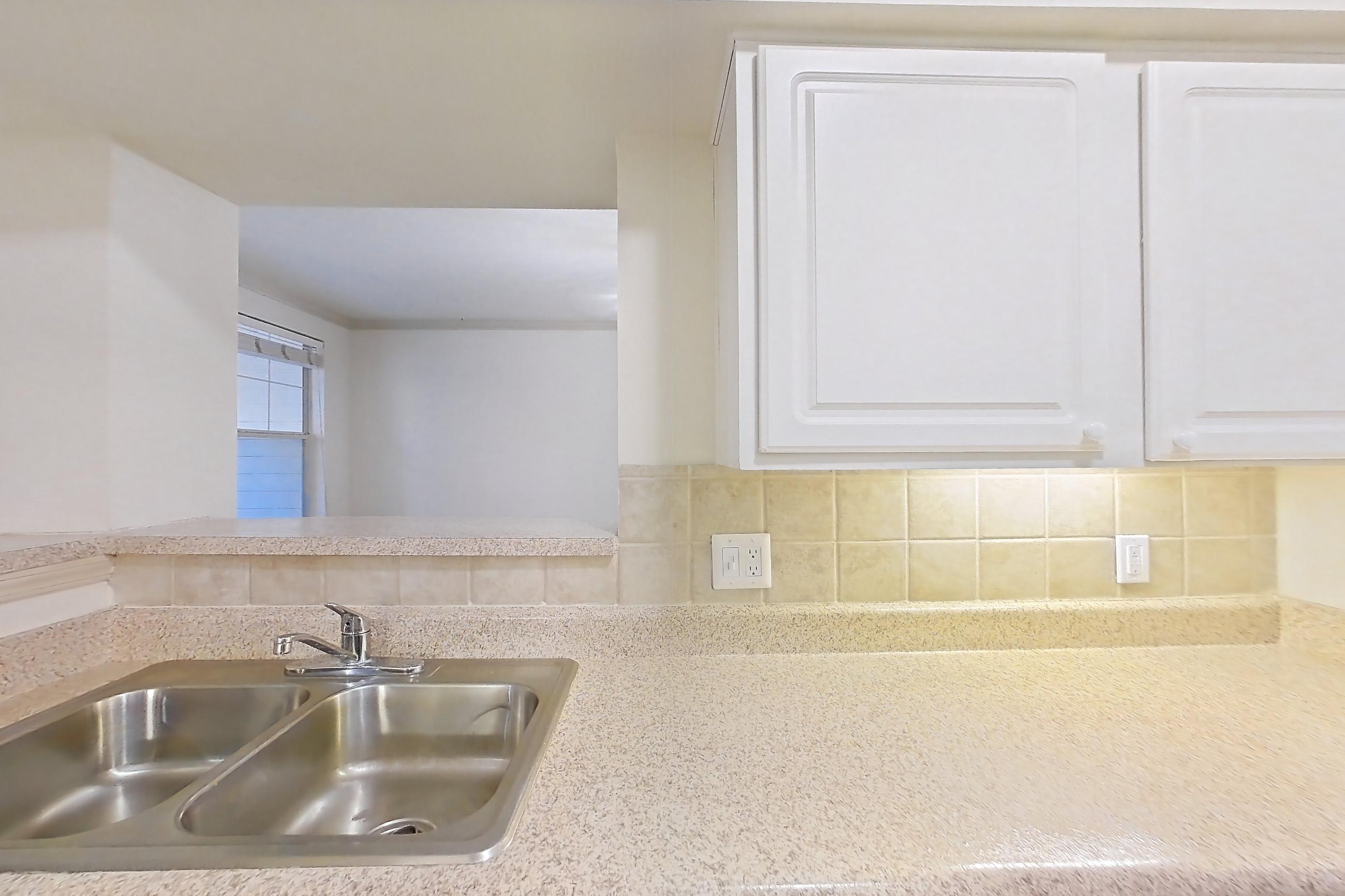 Kitchen with dishwasher, electric range, light countertops, light stone countertops, light wood-finish flooring, microwave, oven/range, refrigerator, and stainless steel appliances, Apartment 3205 at Marq Perimeter