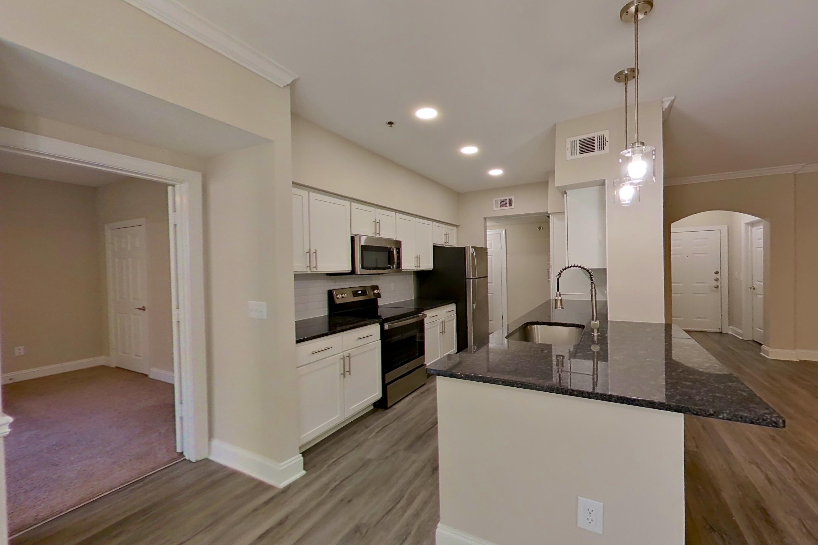 Dining area with dark stone countertops, electric range, light wood-finish flooring, oven/range, and stainless steel appliances, Apartment 3206 at Marq Perimeter