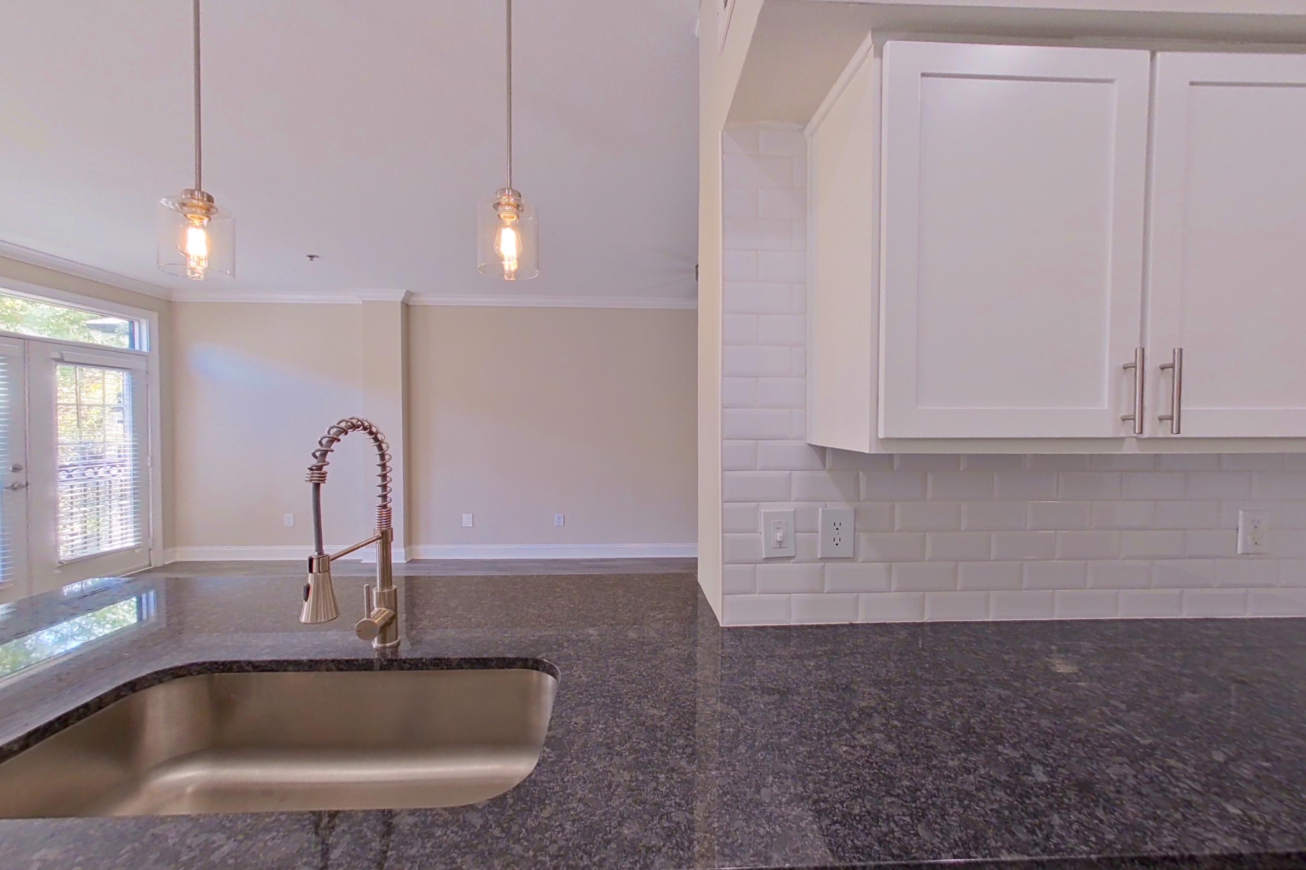 Kitchen with dark stone countertops, dishwasher, electric range, light countertops, light wood-finish flooring, oven/range, refrigerator, and stainless steel appliances, Apartment 3308 at Marq Perimeter