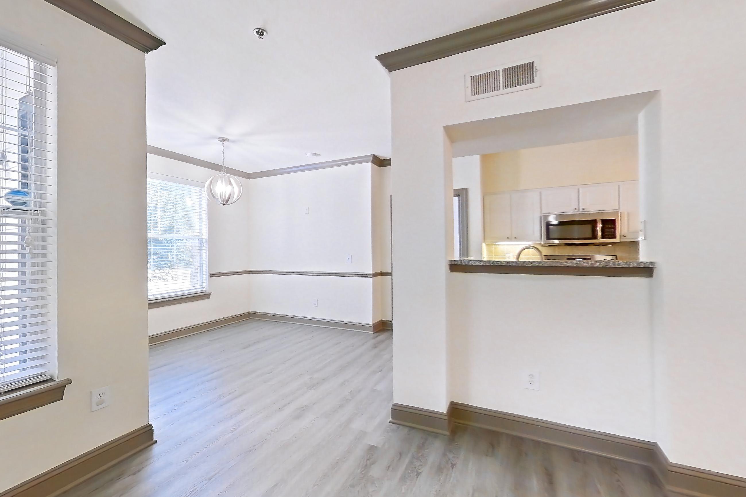 Living room with light wood-finish flooring, microwave, and stainless steel appliances, Apartment 3311 at Marq Perimeter