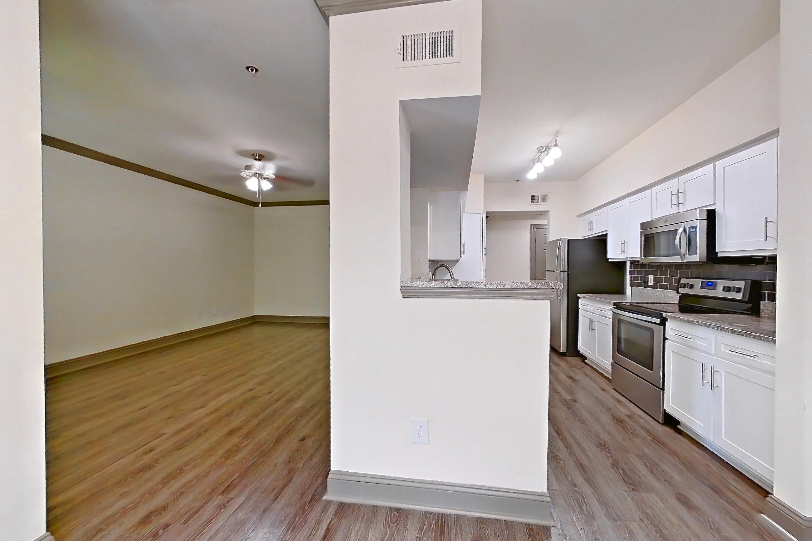 Dining room with electric range, light stone countertops, light wood-finish flooring, microwave, oven/range, and stainless steel appliances, Apartment 3407 at Marq Perimeter