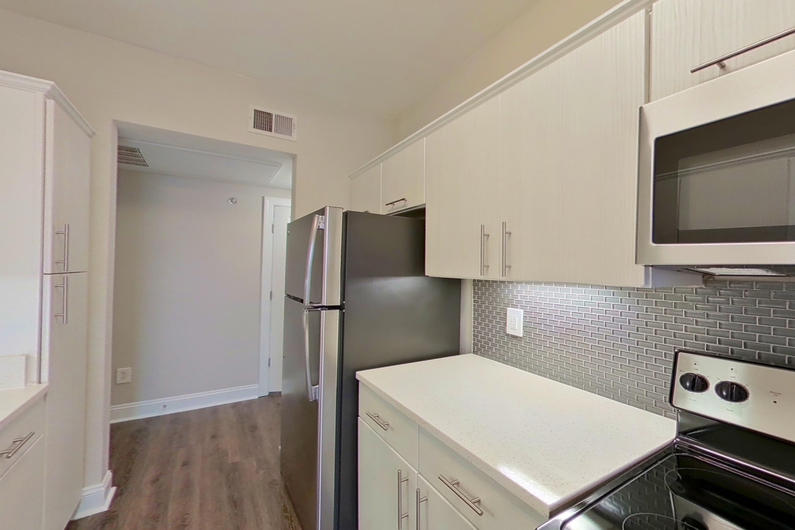 Kitchen with dishwasher, electric range, light countertops, light stone countertops, microwave, oven/range, refrigerator, and stainless steel appliances, Apartment 3508 at Marq Perimeter