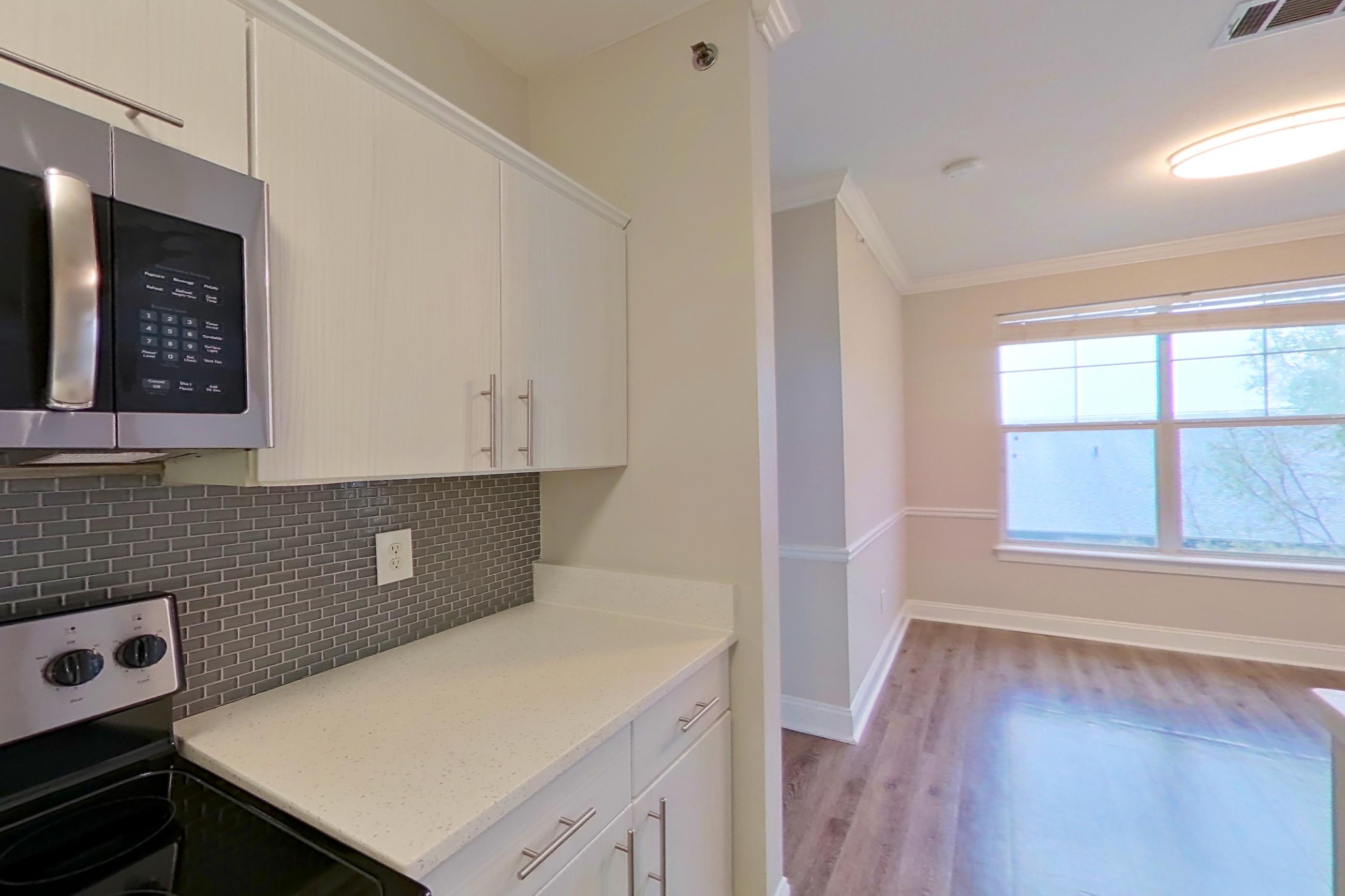 Kitchen with dishwasher, electric range, light countertops, light stone countertops, microwave, oven/range, refrigerator, and stainless steel appliances, Apartment 3508 at Marq Perimeter