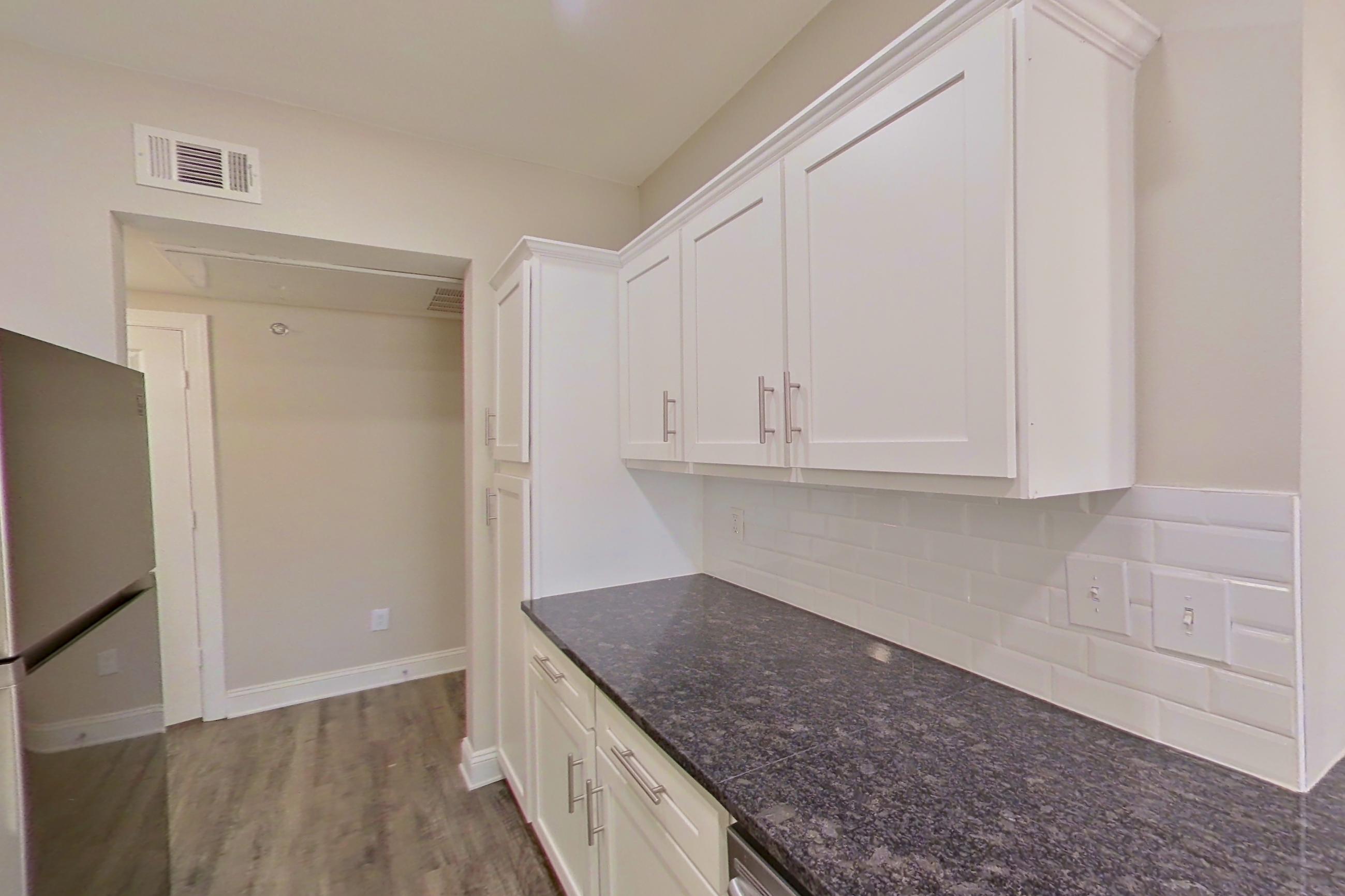 Kitchen with dark stone countertops, dishwasher, electric range, light countertops, oven/range, refrigerator, and stainless steel appliances, Apartment 3509 at Marq Perimeter