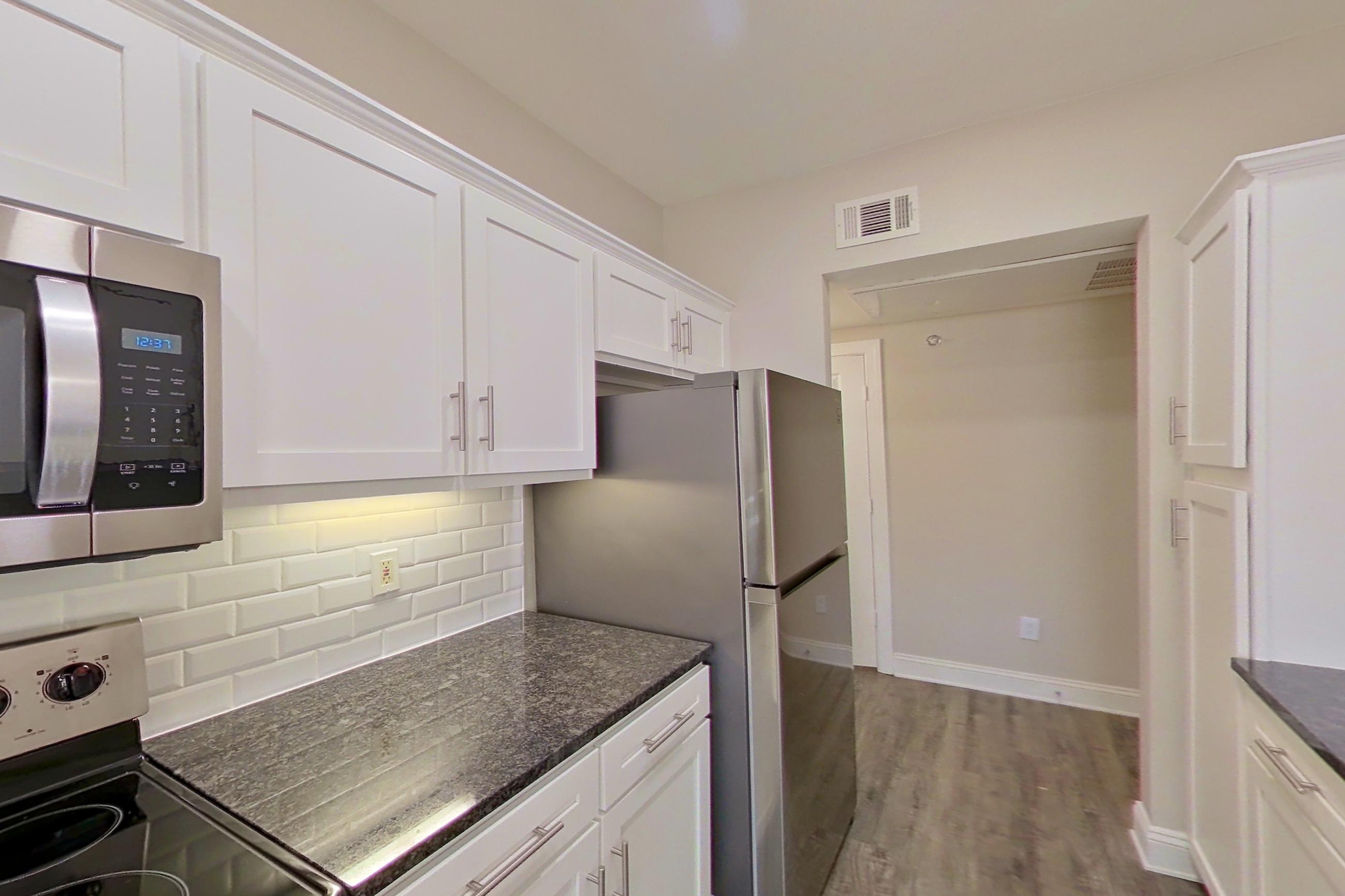 Kitchen with dark stone countertops, dishwasher, electric range, light countertops, oven/range, refrigerator, and stainless steel appliances, Apartment 3509 at Marq Perimeter