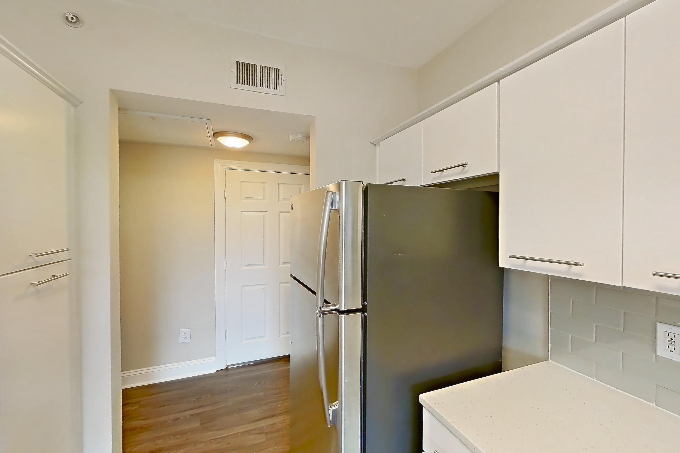 Kitchen with dark wood-finish flooring, dishwasher, electric range, light countertops, light stone countertops, microwave, oven/range, refrigerator, and stainless steel appliances, Apartment 3515 at Marq Perimeter