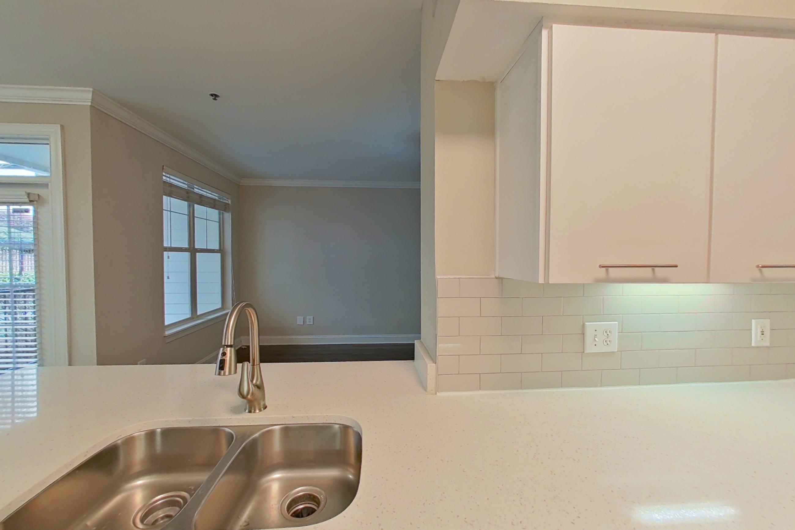 Kitchen with black appliances, dark wood-finish flooring, dishwasher, electric range, light countertops, light wood-finish flooring, microwave, oven/range, refrigerator, and stainless steel appliances, Apartment 4103 at Marq Perimeter