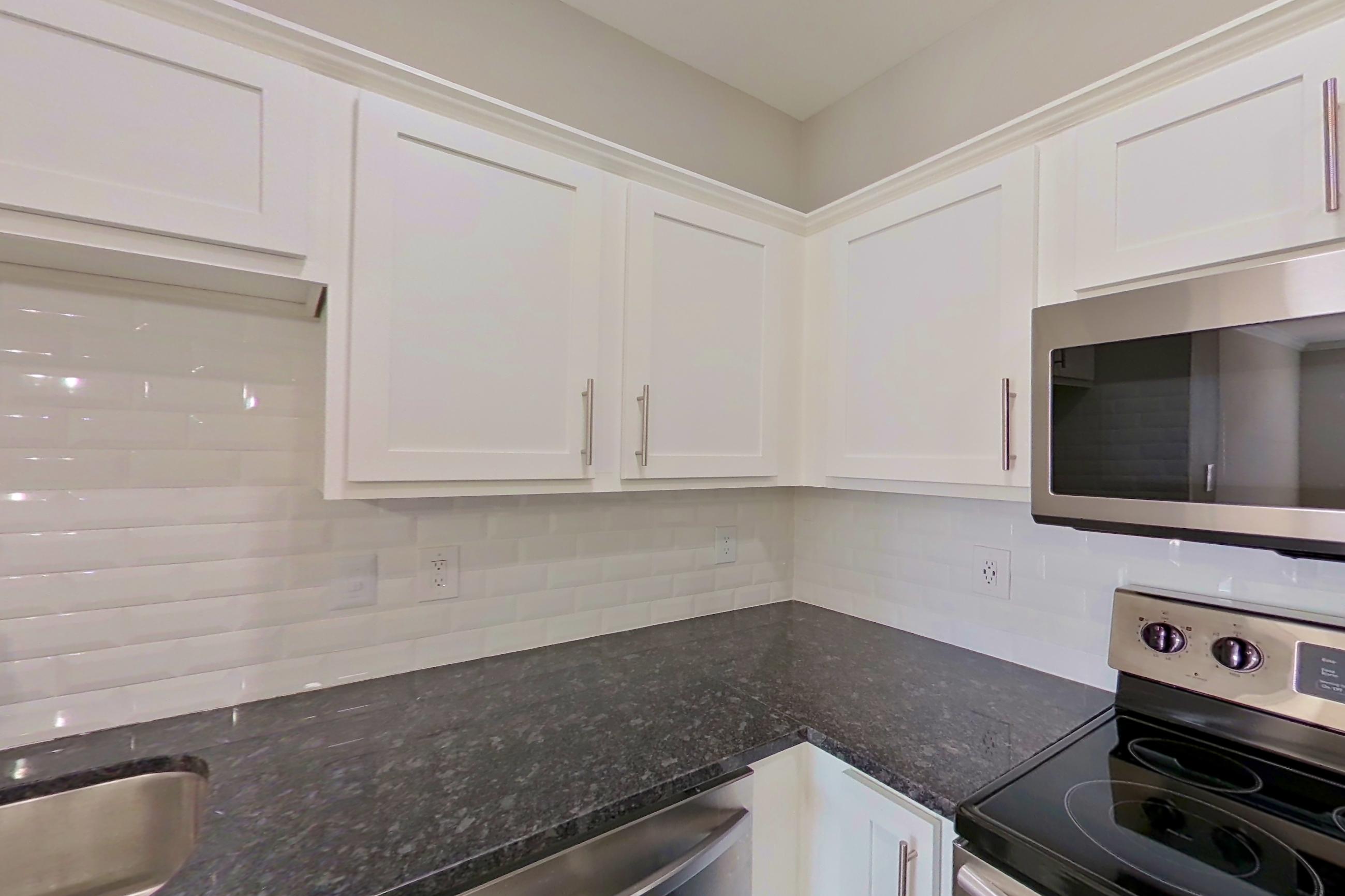 Kitchen with dark stone countertops, dishwasher, electric range, oven/range, refrigerator, and stainless steel appliances, Apartment 4110 at Marq Perimeter