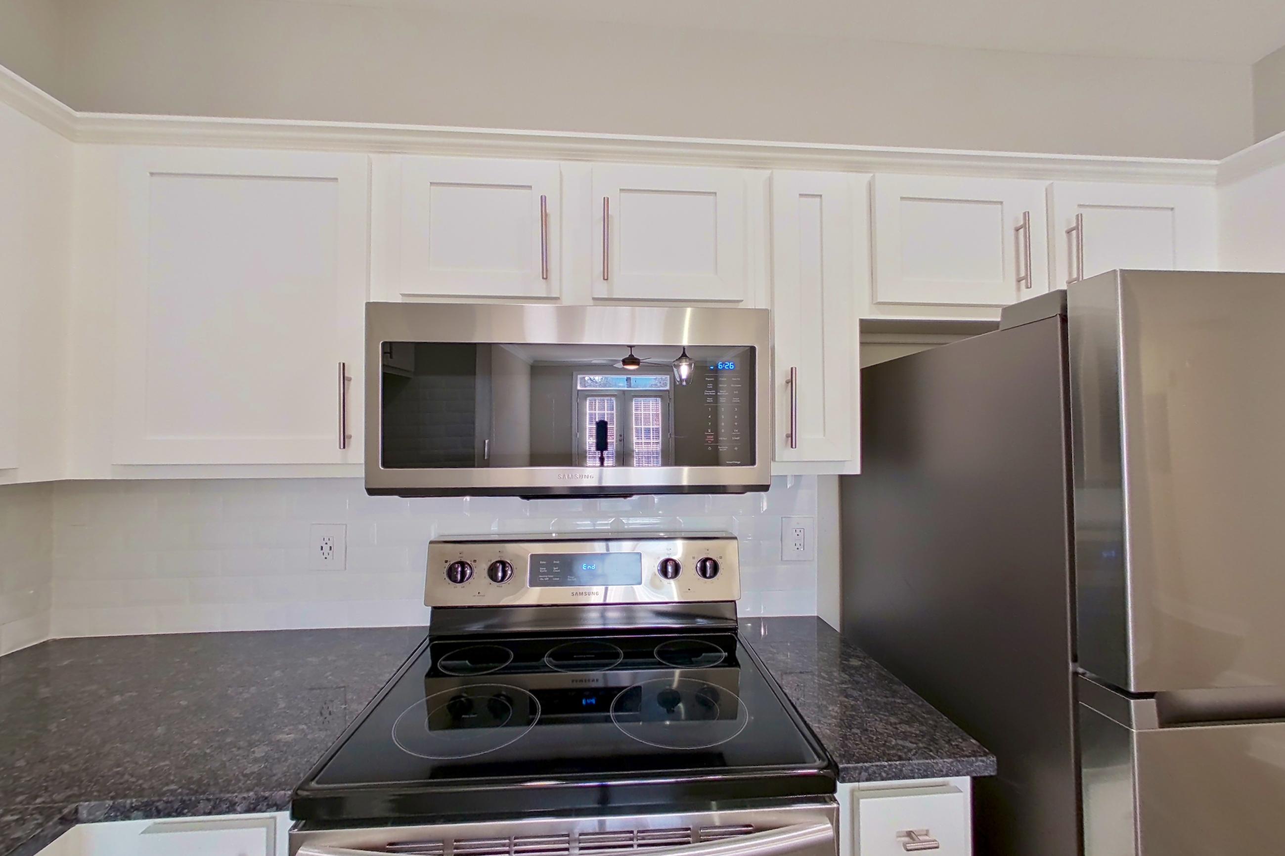 Kitchen with dark stone countertops, dishwasher, electric range, oven/range, refrigerator, and stainless steel appliances, Apartment 4110 at Marq Perimeter