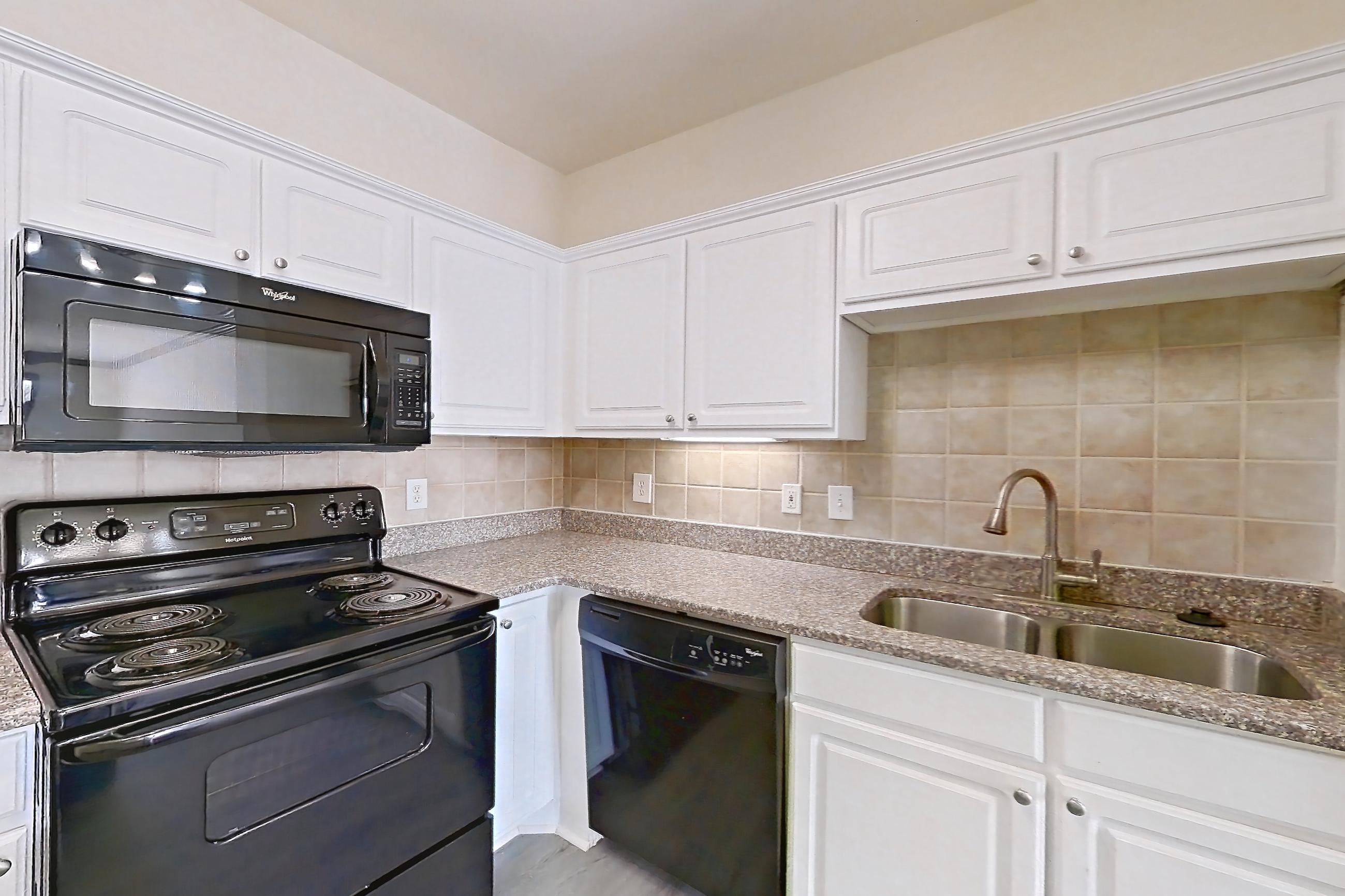 Kitchen with black appliances, dishwasher, electric range, light countertops, light stone countertops, light wood-finish flooring, microwave, and oven/range, Apartment 4208 at Marq Perimeter