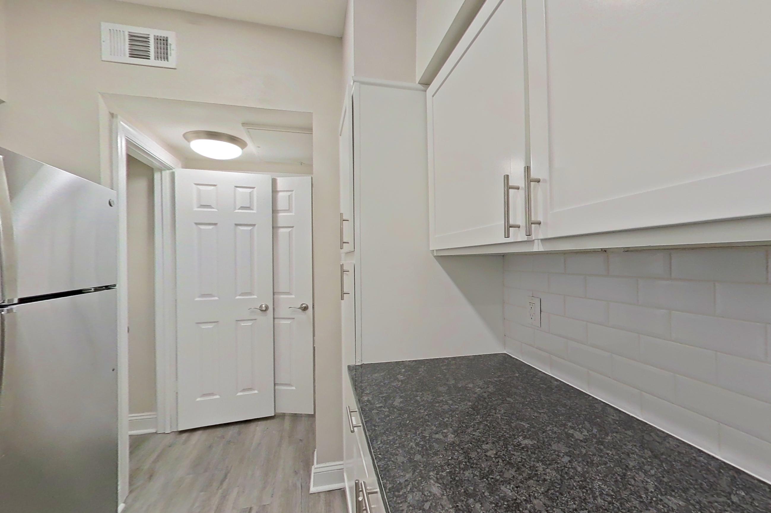 Kitchen with dark stone countertops, electric range, light countertops, light wood-finish flooring, microwave, oven/range, refrigerator, and stainless steel appliances, Apartment 4213 at Marq Perimeter