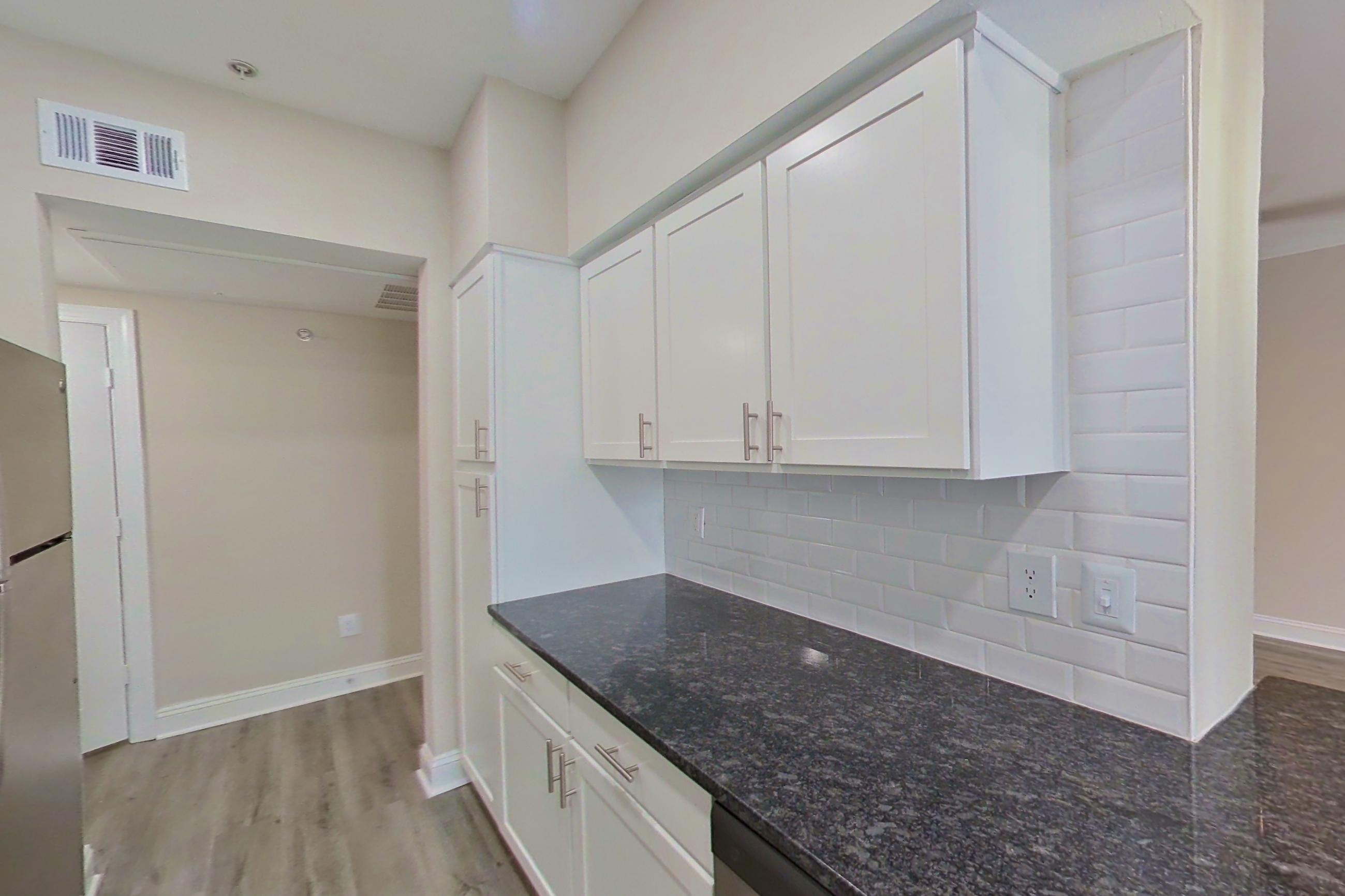 Kitchen with dark stone countertops, electric range, light countertops, light wood-finish flooring, microwave, oven/range, refrigerator, and stainless steel appliances, Apartment 4304 at Marq Perimeter