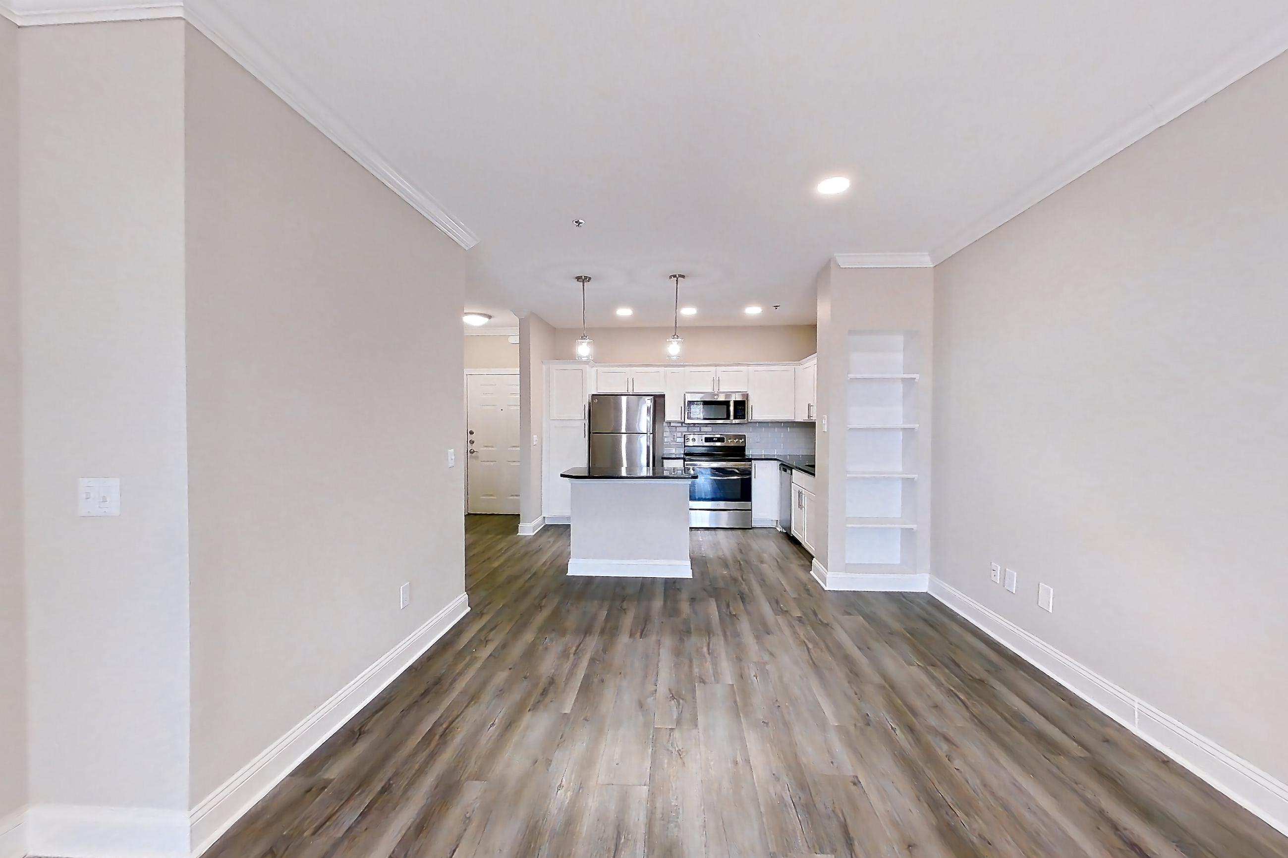 Living room with dark countertops, dark wood-finish flooring, oven/range, refrigerator, and stainless steel appliances, Apartment 4312 at Marq Perimeter
