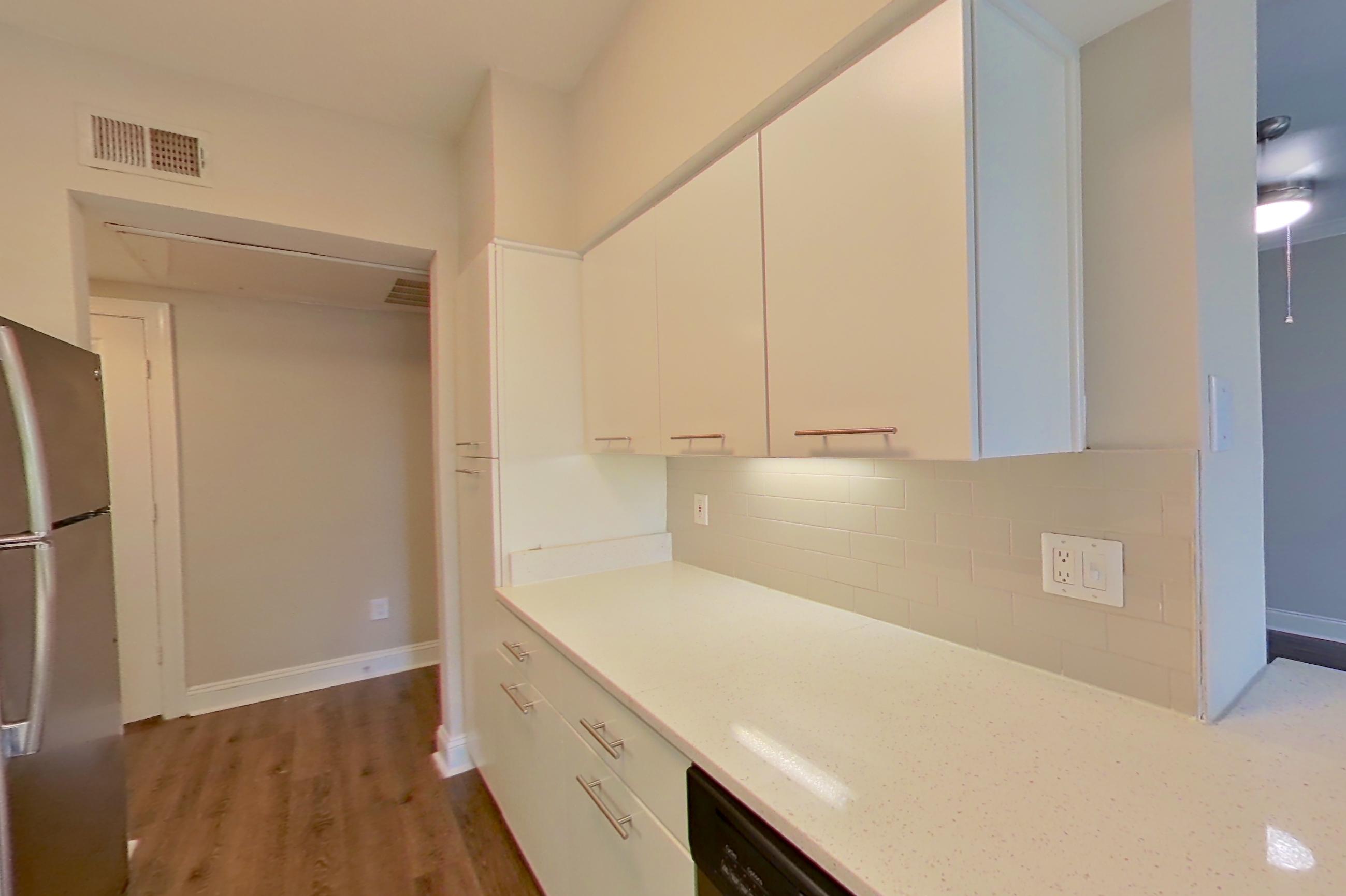 Kitchen with dark wood-finish flooring, dishwasher, electric range, light countertops, light stone countertops, light wood-finish flooring, microwave, oven/range, refrigerator, and stainless steel appliances, Apartment 4404 at Marq Perimeter