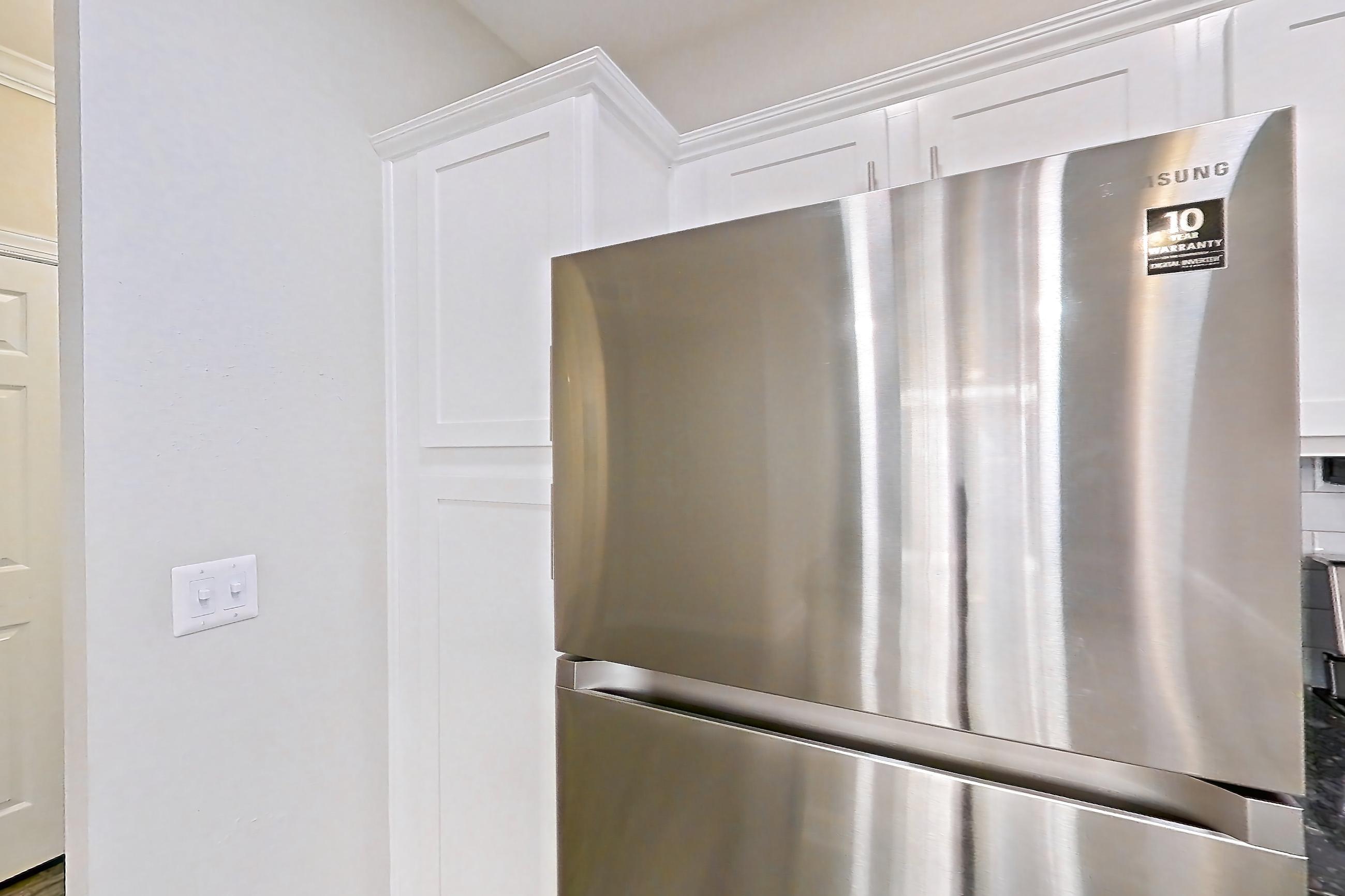 Kitchen with dark countertops, dark stone countertops, dishwasher, electric range, light wood-finish flooring, oven/range, refrigerator, and stainless steel appliances, Apartment 4309 at Marq Perimeter