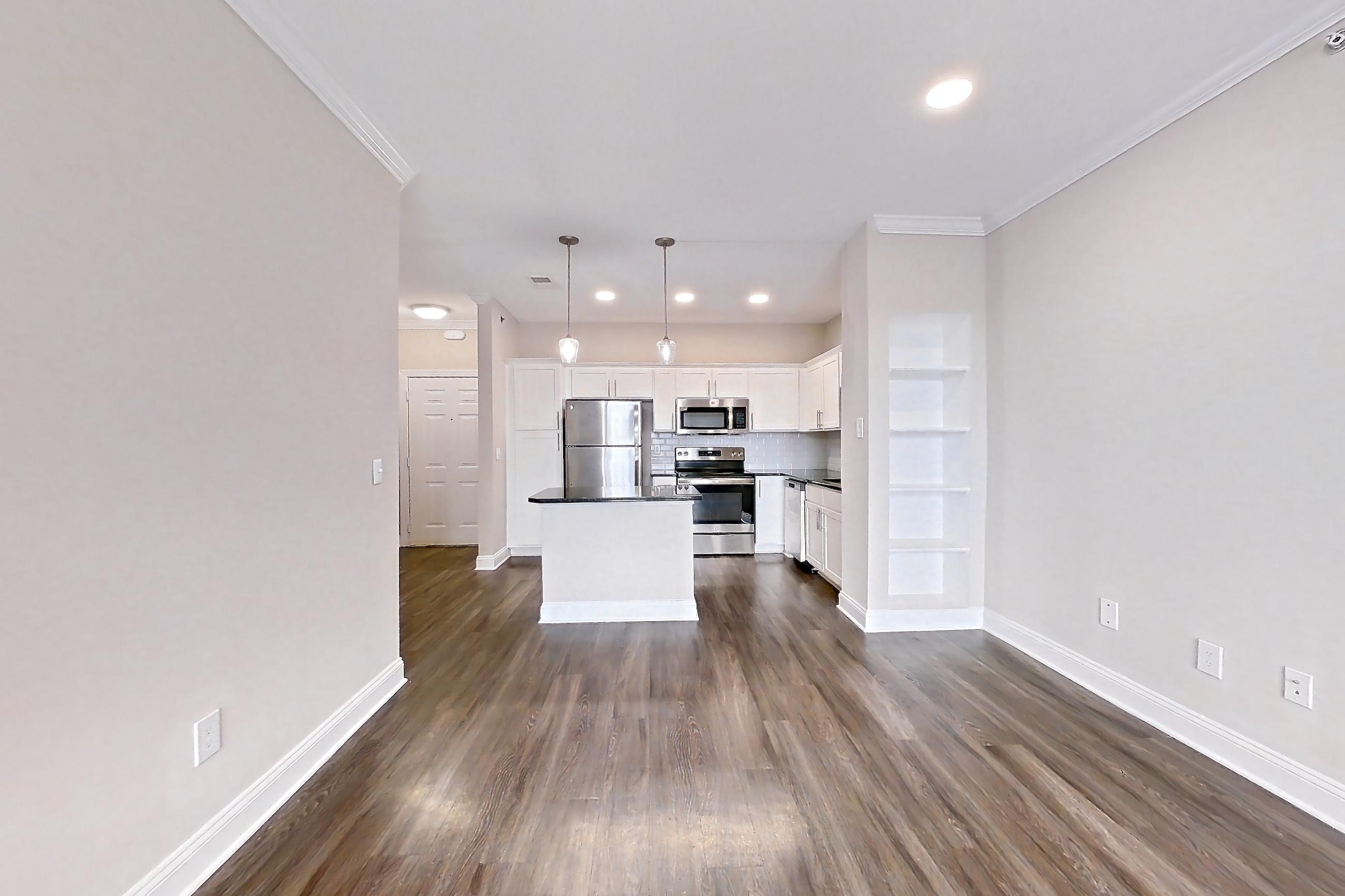 Living room with dark wood-finish flooring, electric range, microwave, oven/range, refrigerator, and stainless steel appliances, Apartment 4508 at Marq Perimeter