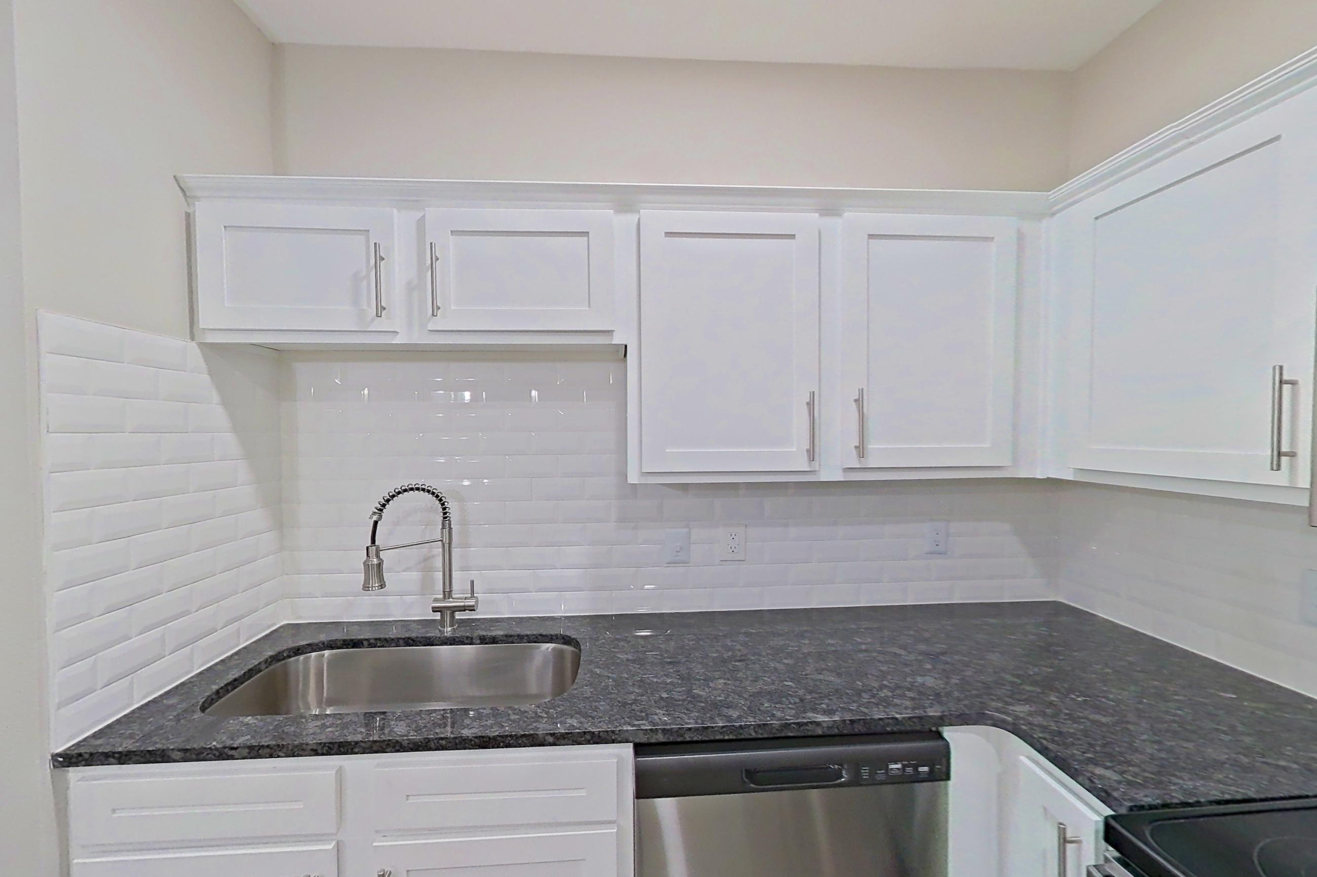 Kitchen with dark stone countertops, dishwasher, electric range, light countertops, light wood-finish flooring, microwave, oven/range, refrigerator, and stainless steel appliances, Apartment 5209 at Marq Perimeter