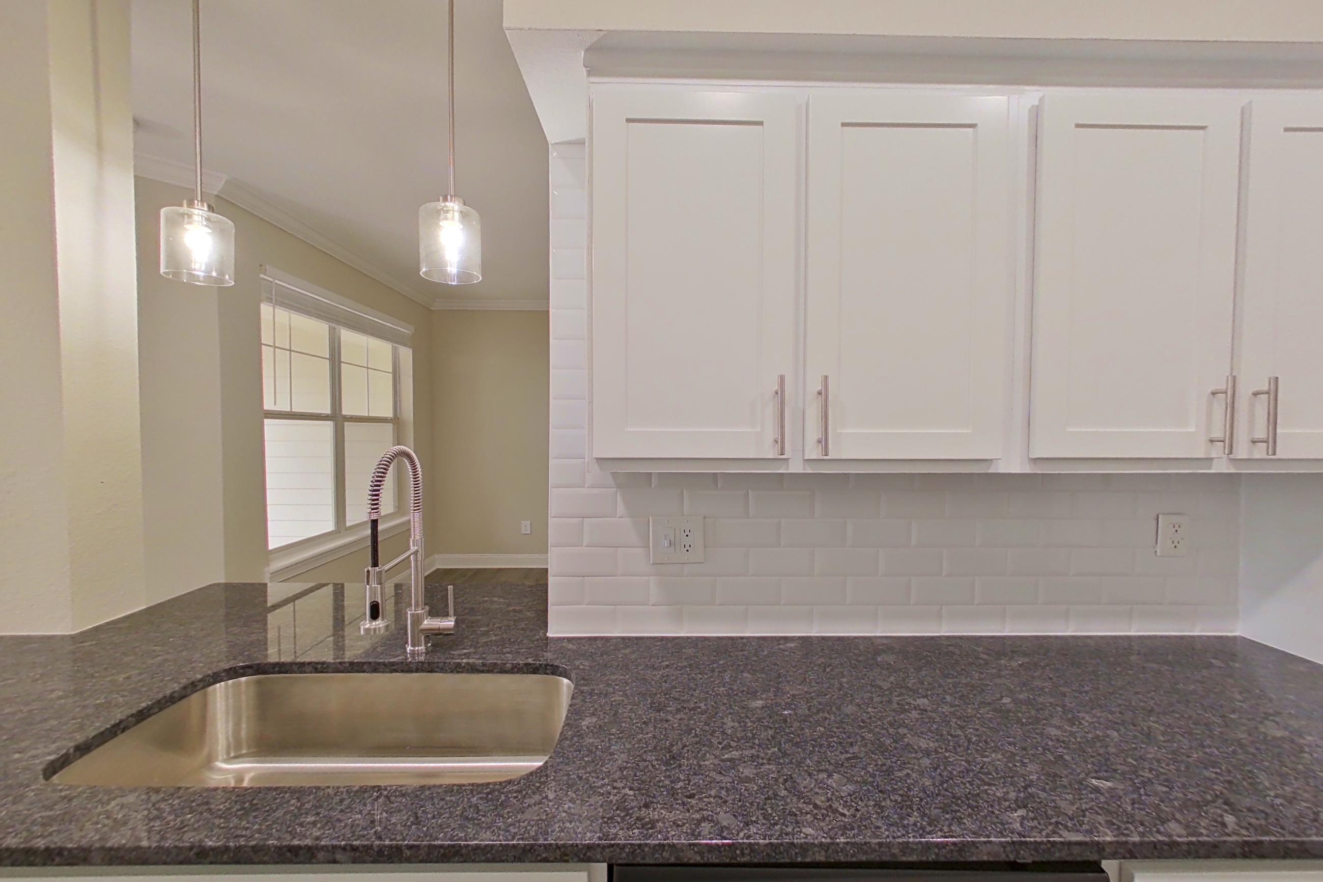 Kitchen with dark stone countertops, dishwasher, electric range, light countertops, light wood-finish flooring, microwave, oven/range, refrigerator, and stainless steel appliances, Apartment 5213 at Marq Perimeter