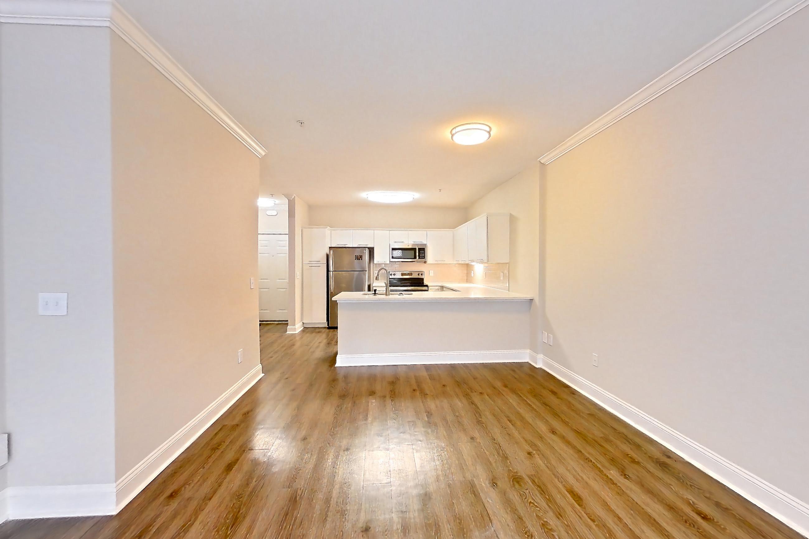 Living room with dark wood-finish flooring, microwave, and stainless steel appliances, Apartment 5303 at Marq Perimeter