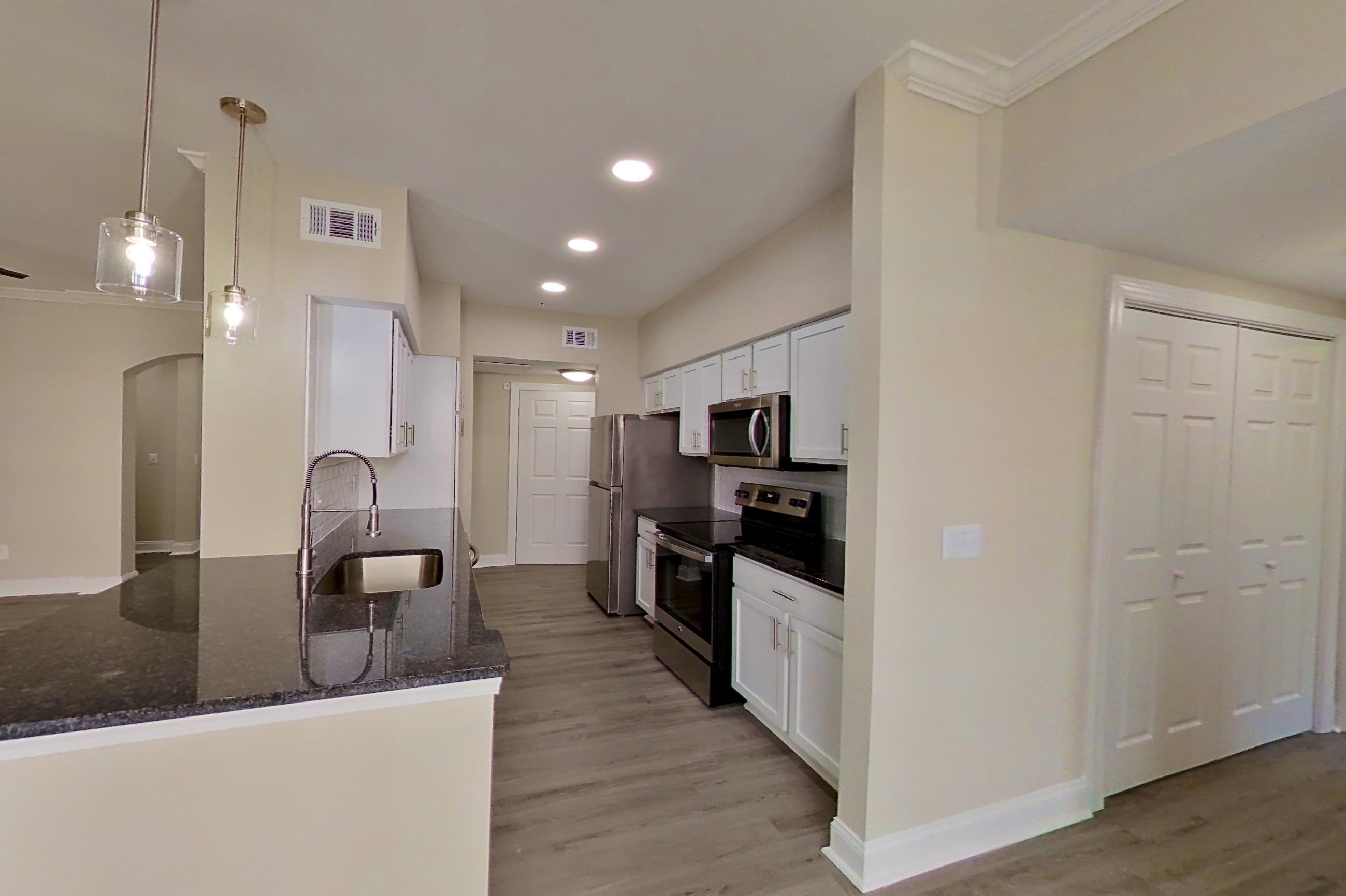 Dining area with dark countertops, electric range, light wood-finish flooring, microwave, oven/range, refrigerator, and stainless steel appliances, Apartment 5313 at Marq Perimeter