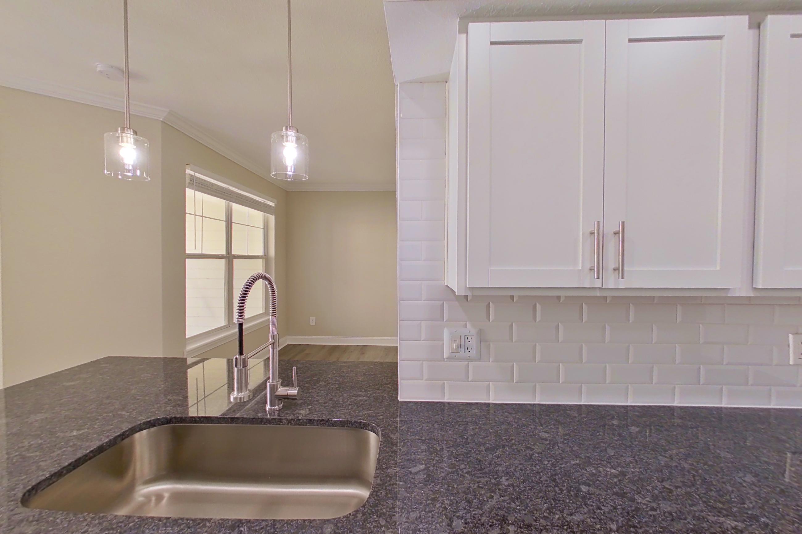 Kitchen with dark stone countertops, dishwasher, electric range, light countertops, light wood-finish flooring, microwave, oven/range, refrigerator, and stainless steel appliances, Apartment 5313 at Marq Perimeter