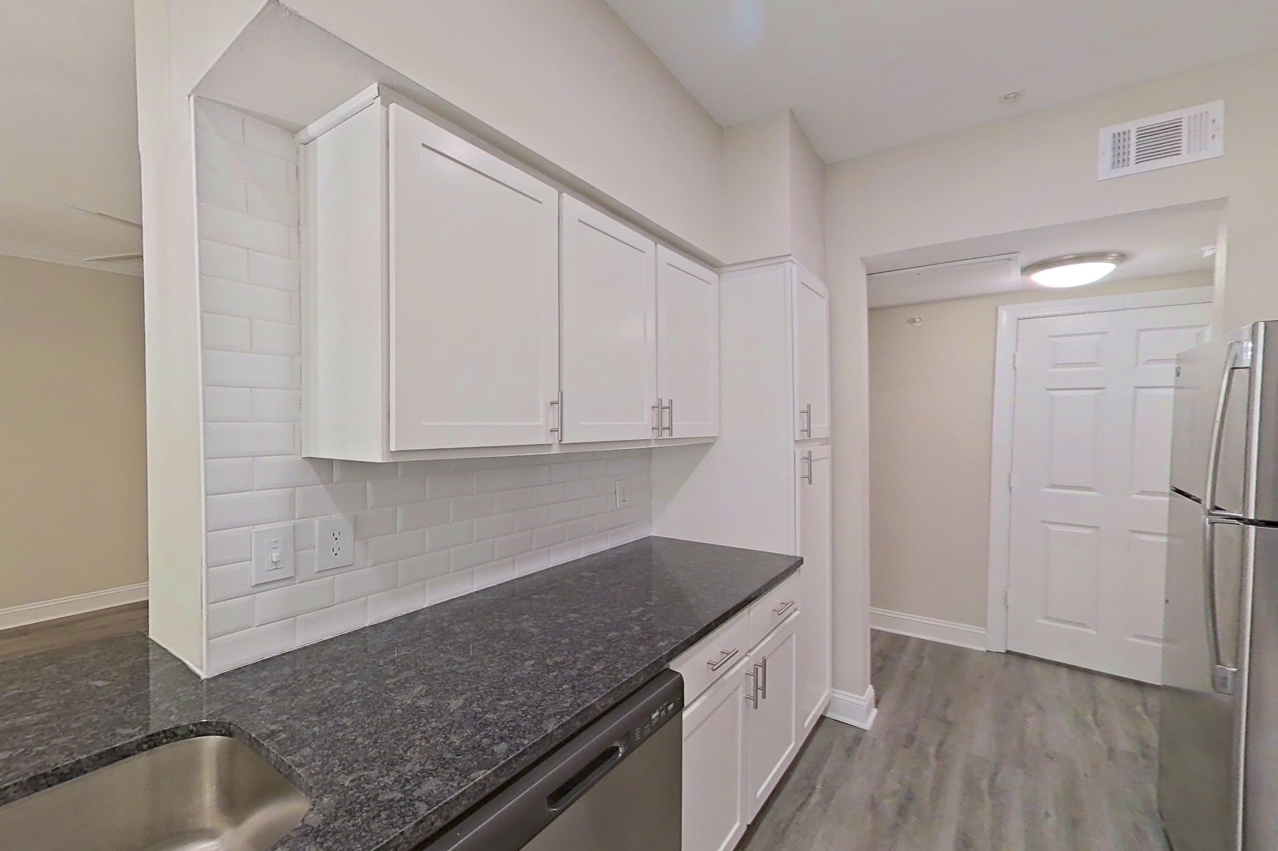 Kitchen with dark stone countertops, dishwasher, electric range, light countertops, light wood-finish flooring, microwave, oven/range, refrigerator, and stainless steel appliances, Apartment 5401 at Marq Perimeter
