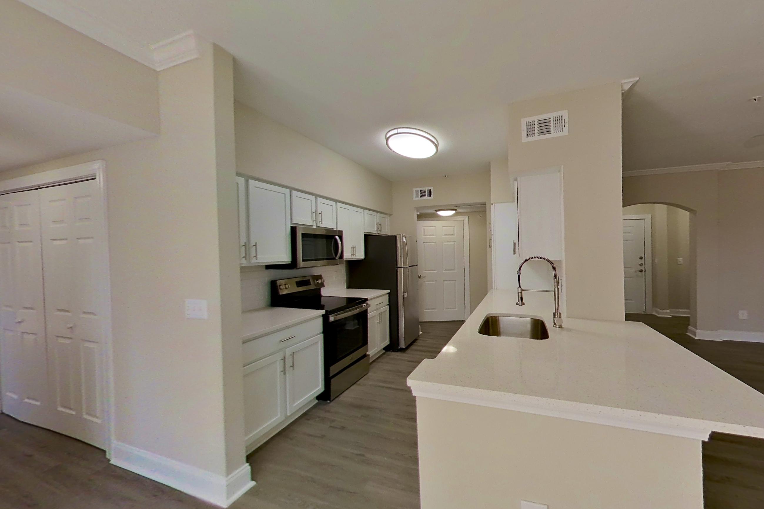Dining area with electric range, light countertops, light wood-finish flooring, microwave, oven/range, refrigerator, and stainless steel appliances, Apartment 5412 at Marq Perimeter