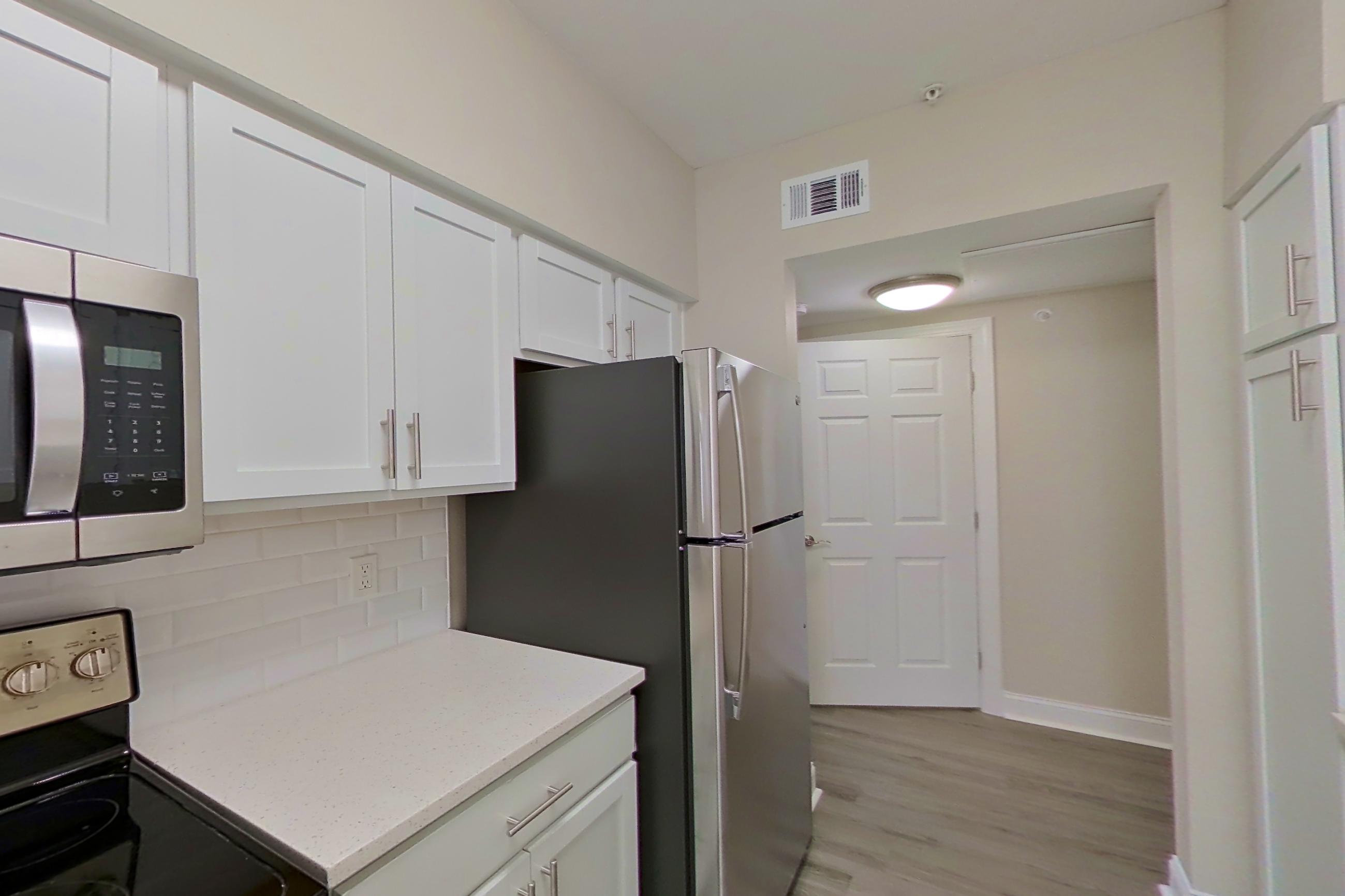 Kitchen with electric range, light countertops, light stone countertops, light wood-finish flooring, oven/range, refrigerator, and stainless steel appliances, Apartment 5412 at Marq Perimeter