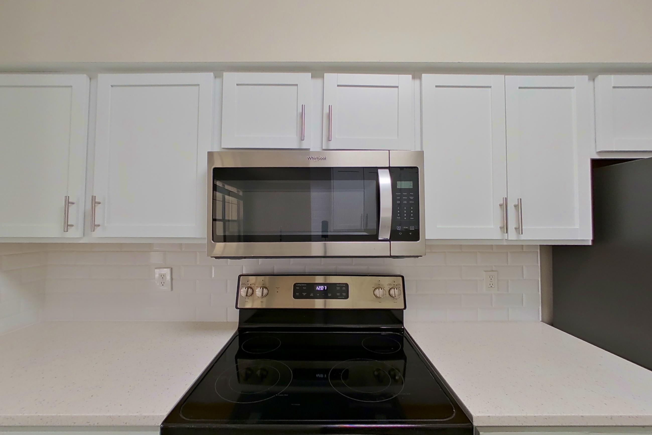Kitchen with electric range, light countertops, light stone countertops, light wood-finish flooring, oven/range, refrigerator, and stainless steel appliances, Apartment 5412 at Marq Perimeter
