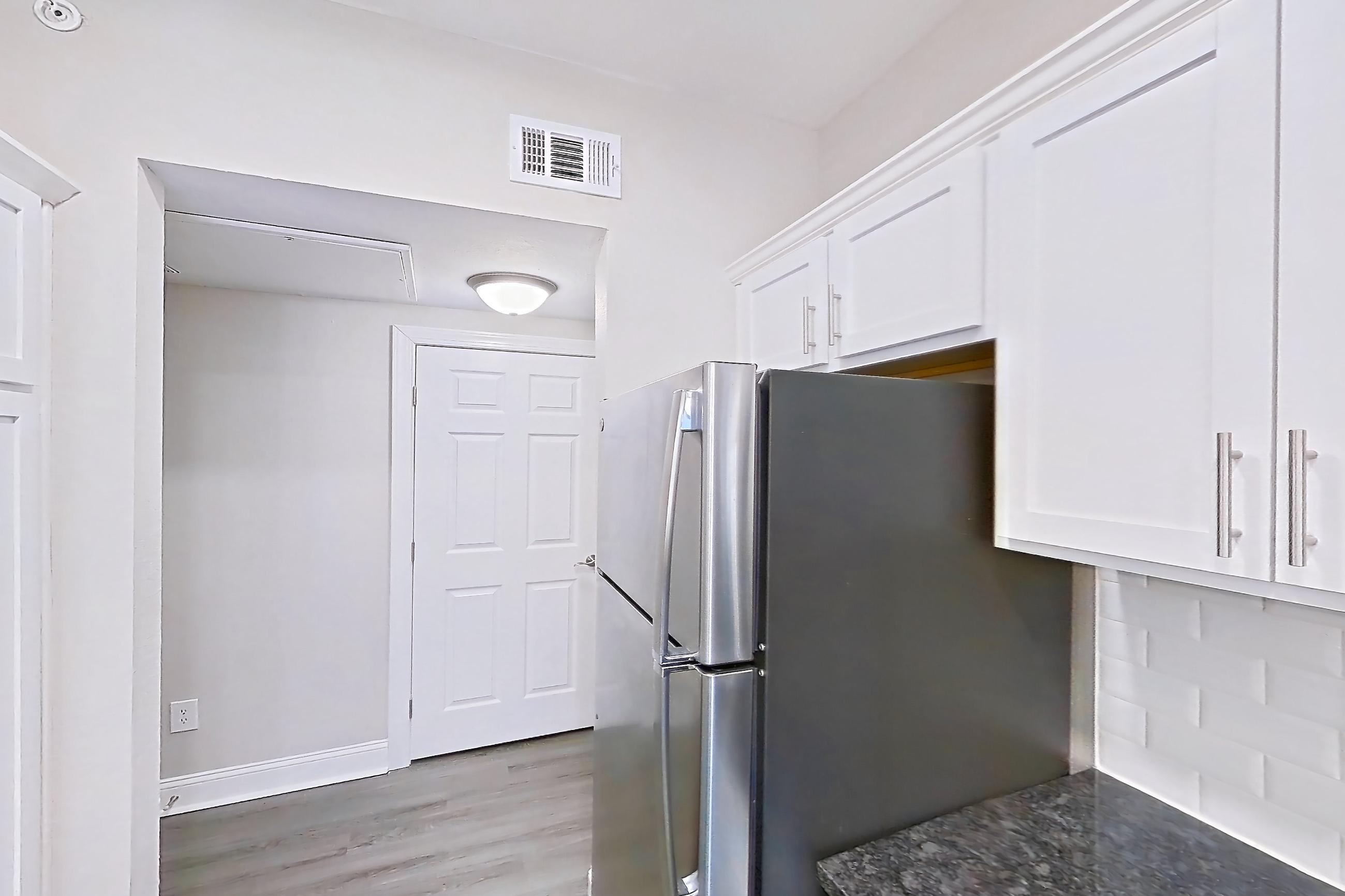 Kitchen with dark stone countertops, dishwasher, electric range, light countertops, light wood-finish flooring, oven/range, refrigerator, and stainless steel appliances, Apartment 5513 at Marq Perimeter