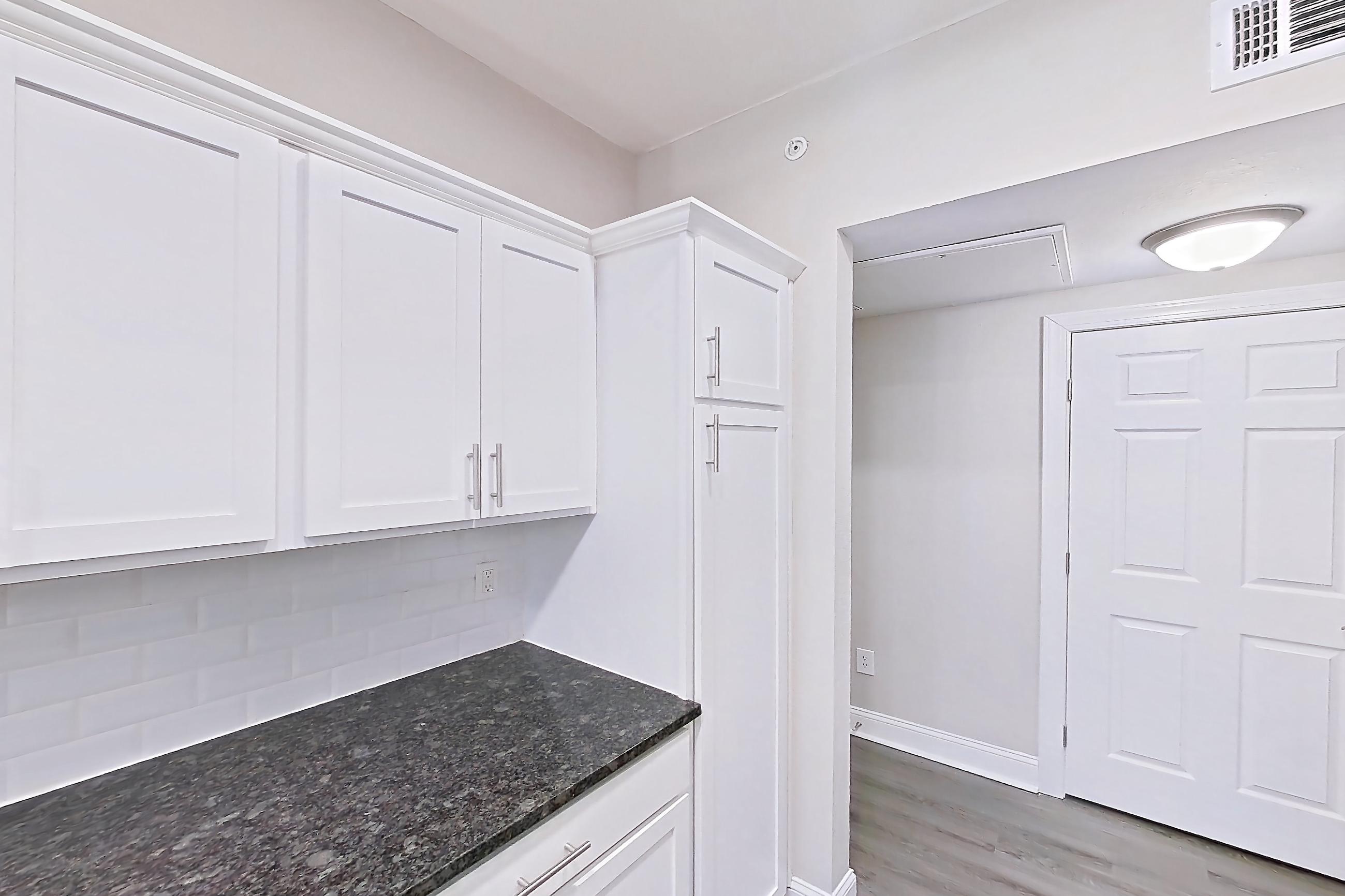Kitchen with dark stone countertops, dishwasher, electric range, light countertops, light wood-finish flooring, oven/range, refrigerator, and stainless steel appliances, Apartment 5513 at Marq Perimeter